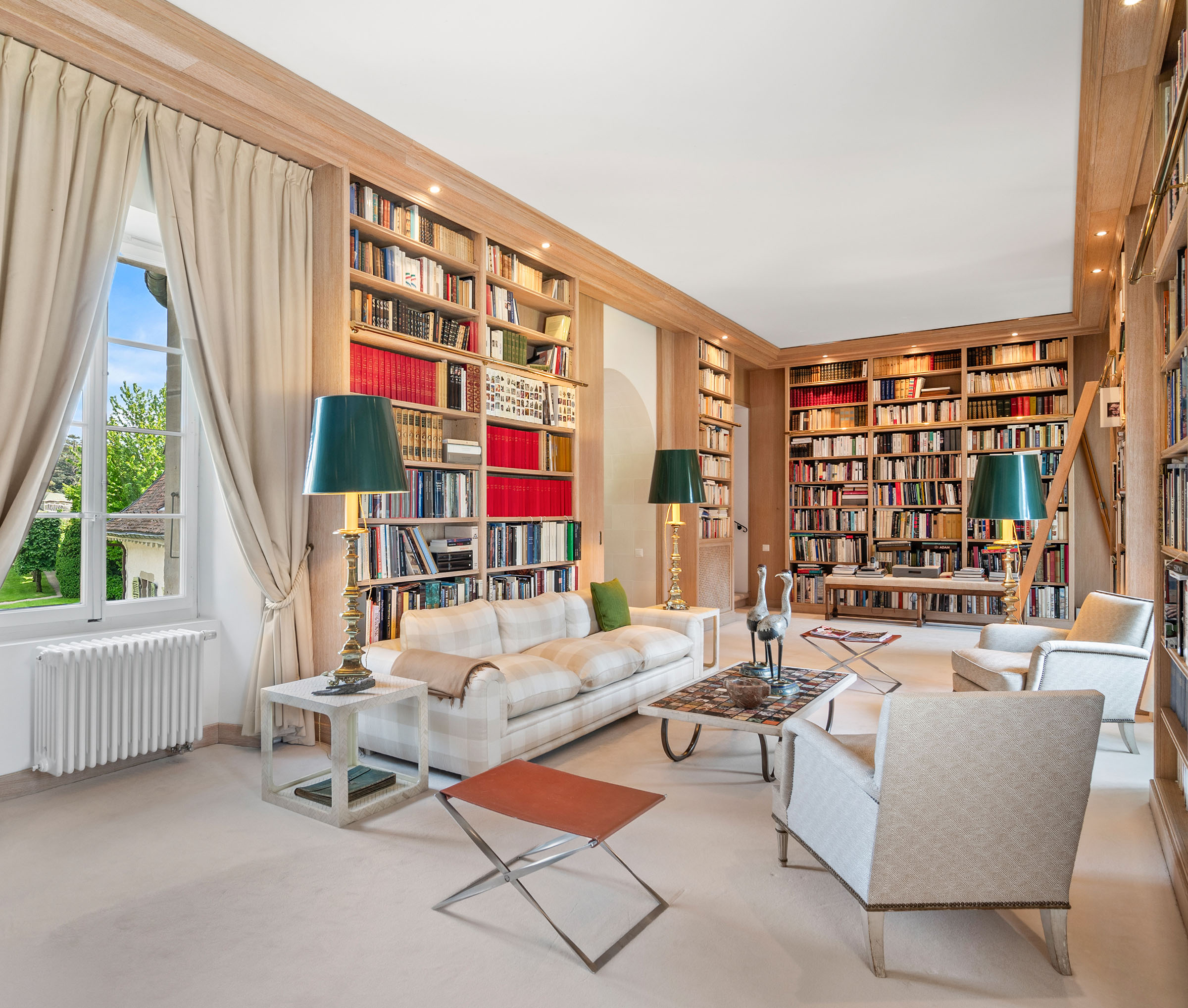 The less formal living room in the Chateau de Tournay is a perfect space for moments of leisure, with floor-to-ceiling bookshelves and views of the garden