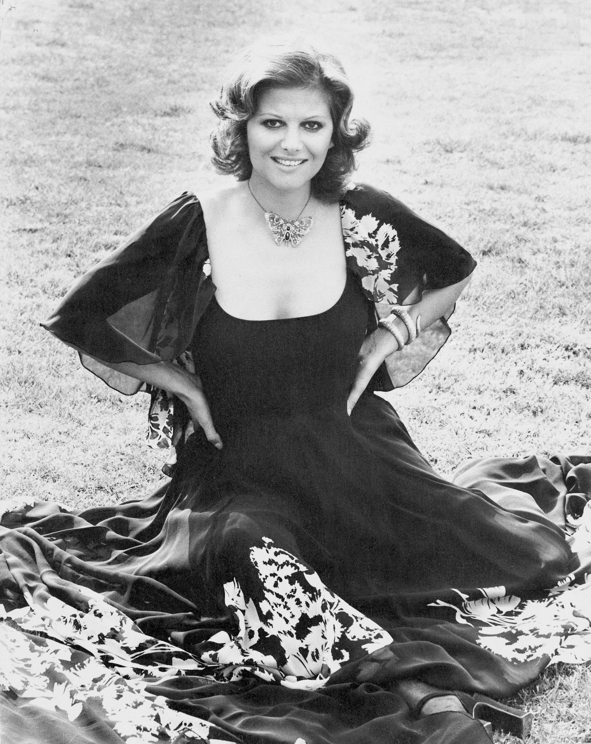 Claudia Cardinale in 1974. She is wearing a 19th-century ruby, sapphire and diamond butterfly brooch as a necklace, and a Bulgari Serpenti bracelet watch, both offered in Joaillerie Paris, until 26 June 2026 at Christie's Online