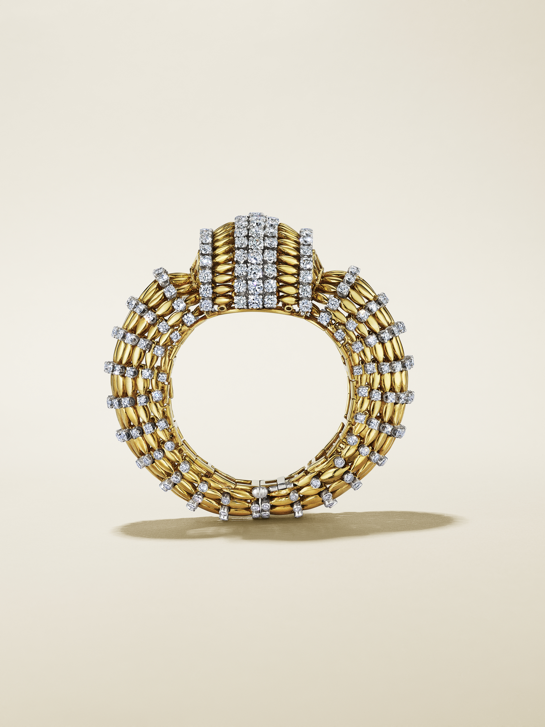 A gold circular ring adorned with rows of sparkling diamonds on a plain background.