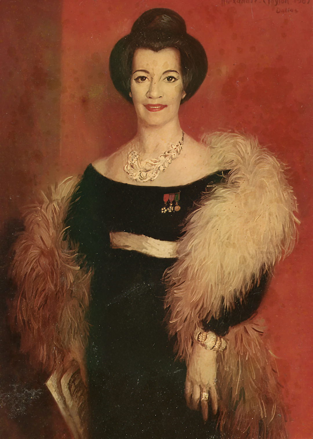 A woman in elegant attire with a fur stole and jewelry stands against a red background.