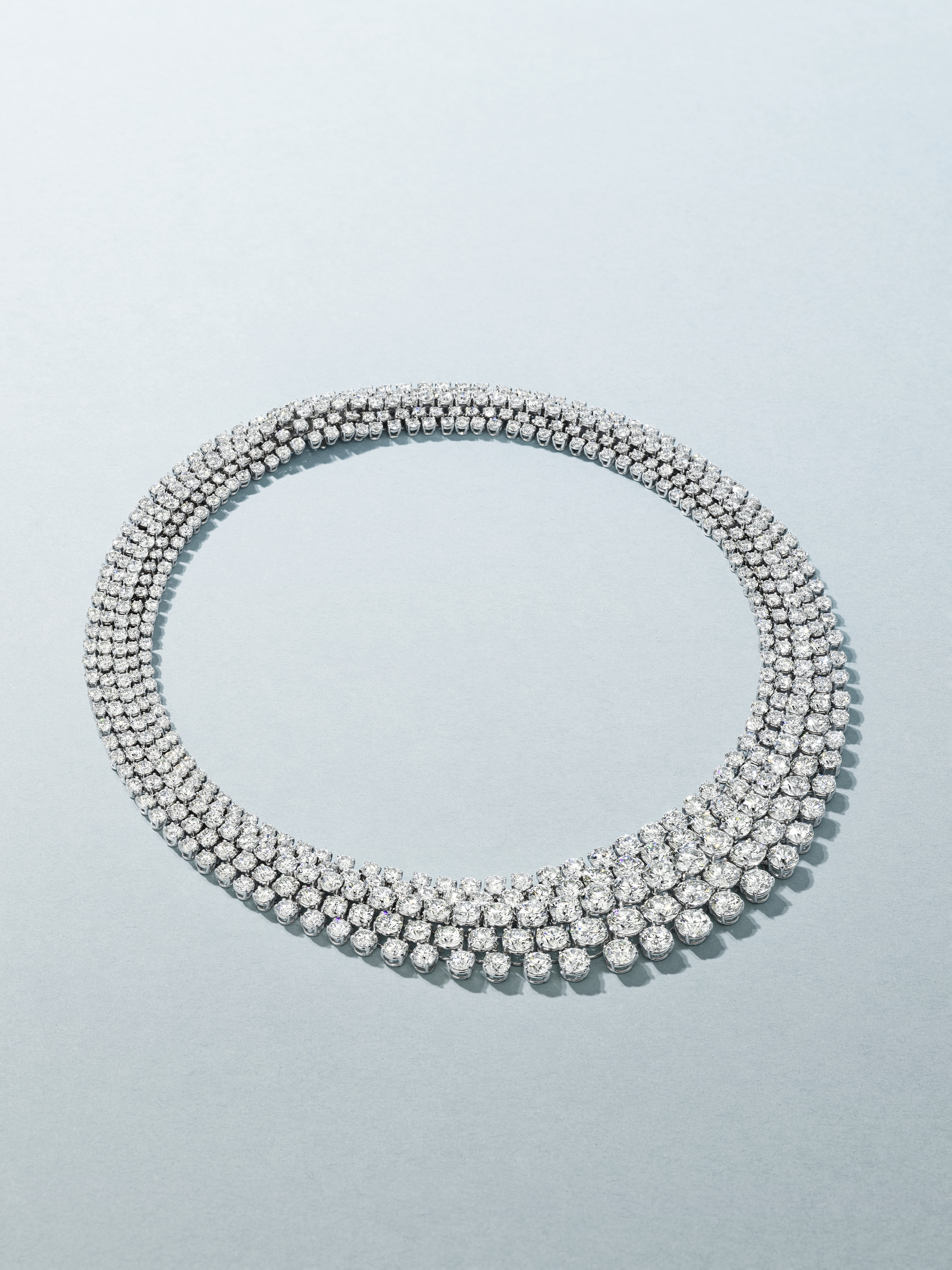 A luxurious diamond necklace with three rows of sparkling round stones.