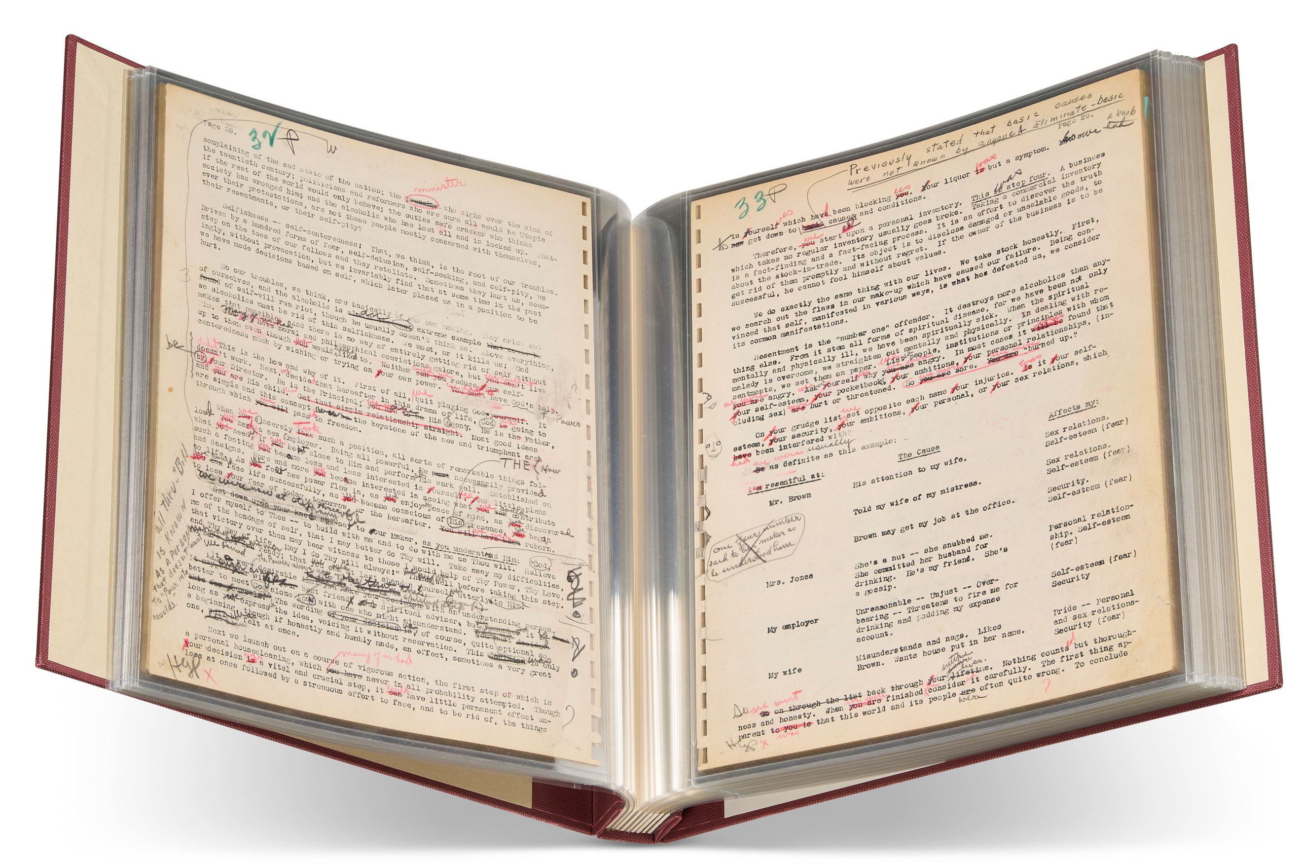An open book with heavily annotated typed pages, featuring handwritten edits in red and black ink.