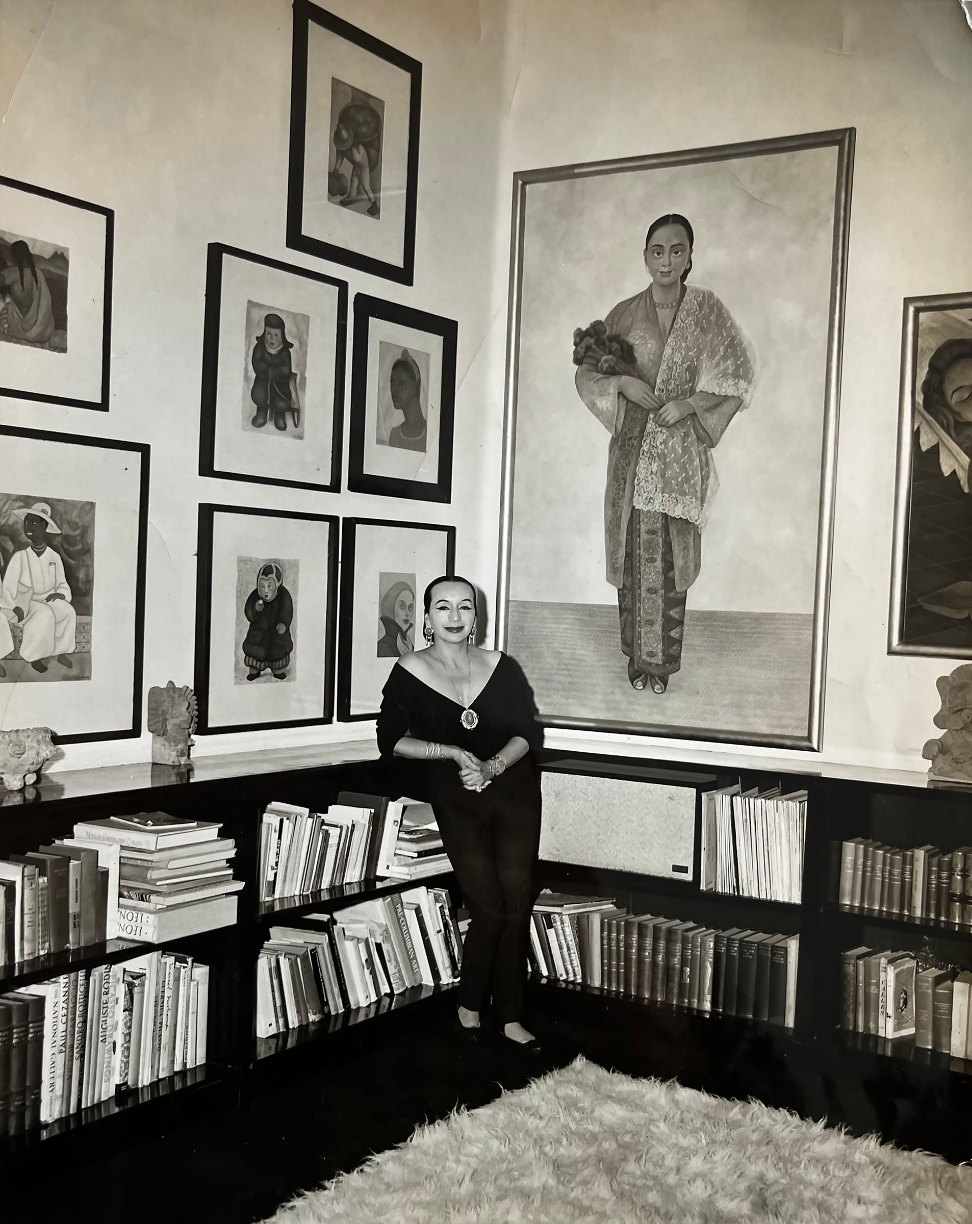 Dolores Olmedo in the library at Hacienda La Noria, surrounded by her books and works by Diego Rivera