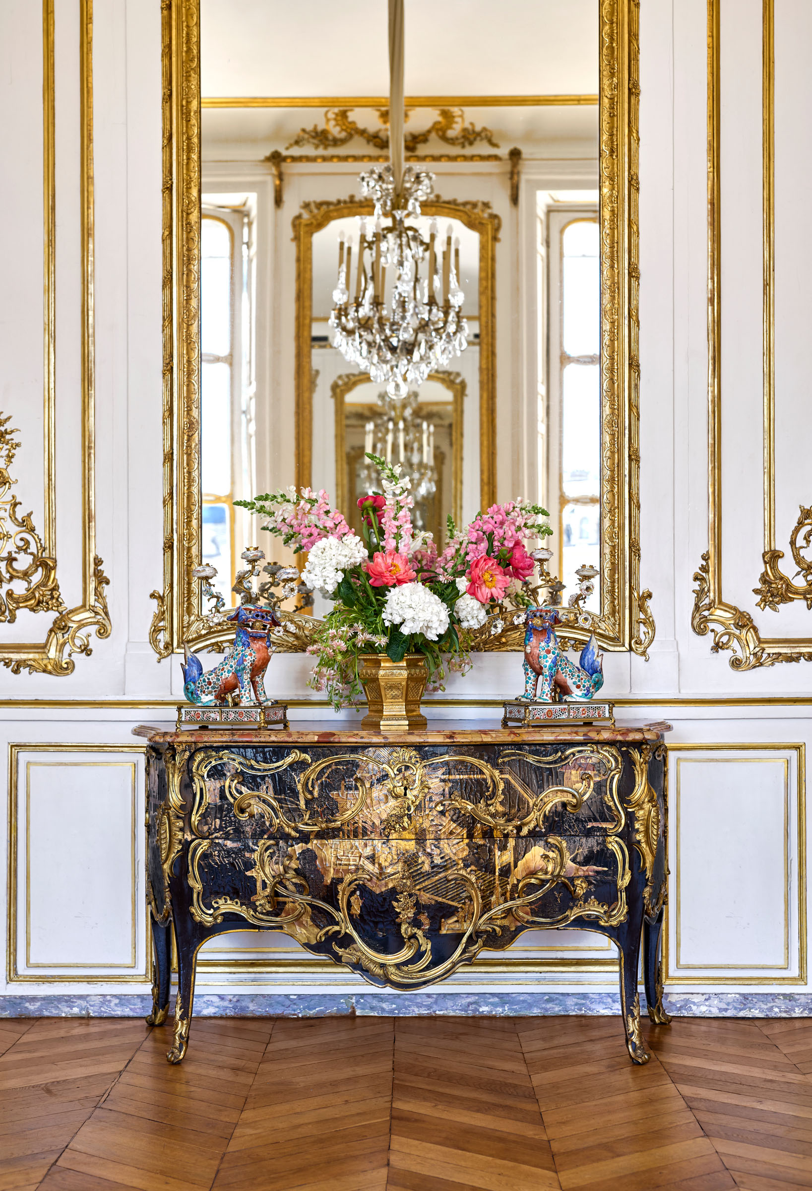 In the grand salon of the Hotel Blumenthal, a Louis XV ormolu-mounted Chinese lacquer commode, stamped by Mathieu Criaerd, circa 1745-49, on top of which is a Regence gilt-bronze wine cooler, circa 1715, flanked by a pair of candelabra in the form of Japanese guardian lions. All offered in the Graziella Patino de Ortiz Linares Collection - Evening Sale on 23 September 2026 at Christie's in Paris