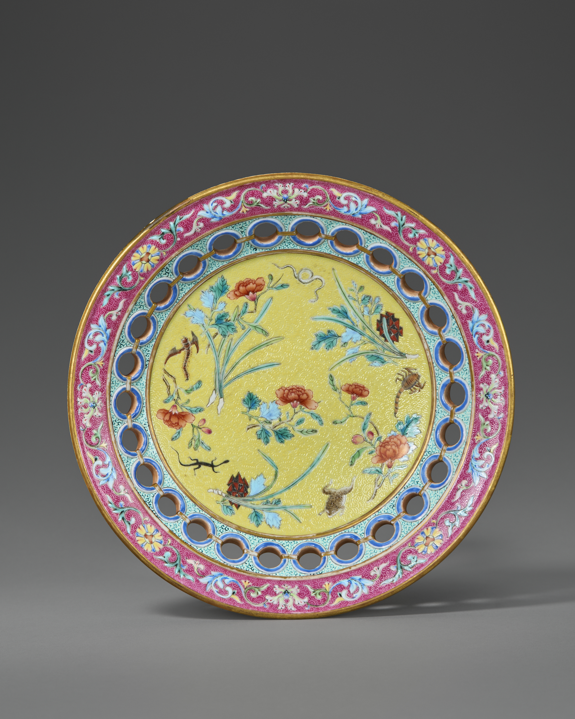 A decorative plate with floral patterns on a yellow background and a pink ornate border.