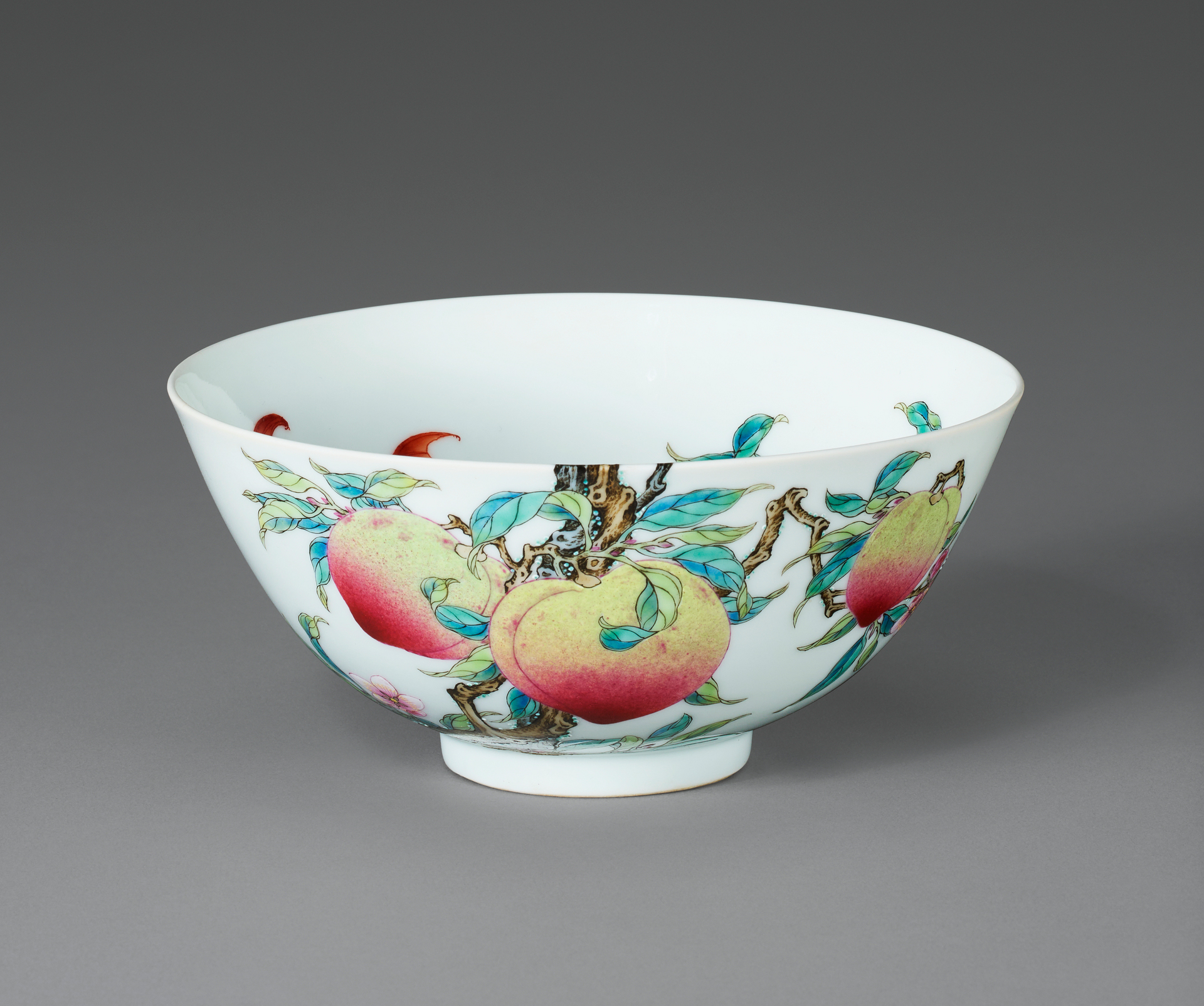 A porcelain bowl with colorful peaches and leaves painted on its exterior.