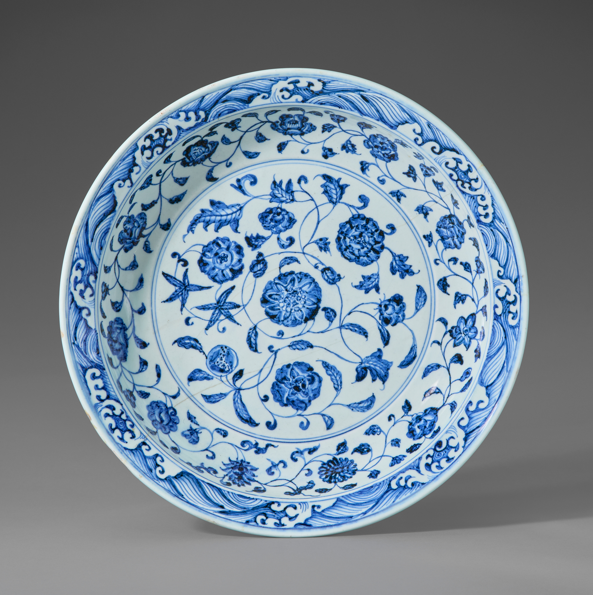 A blue and white porcelain plate with intricate floral and wave patterns.