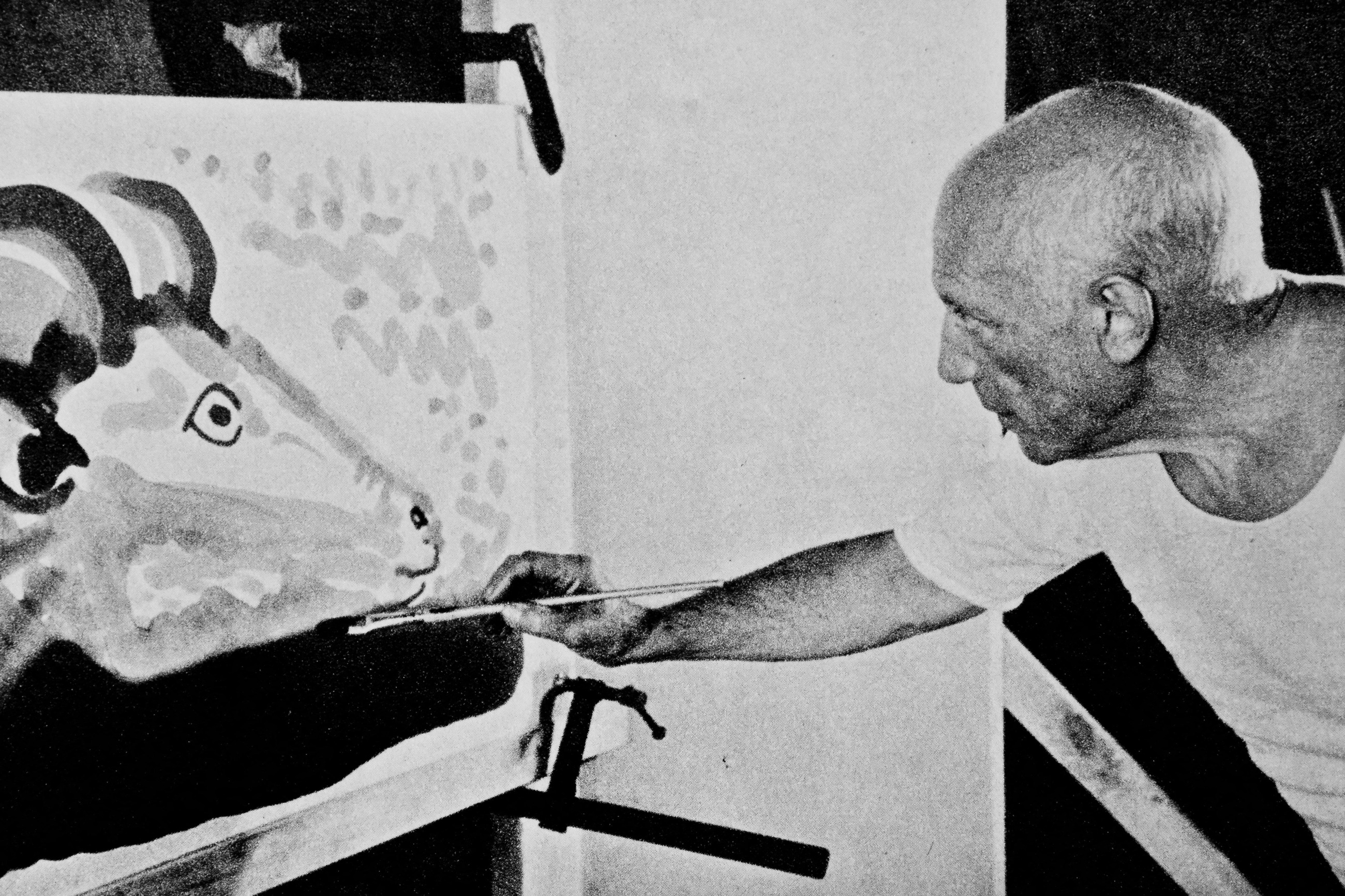 A man is painting an abstract image of a ram on a canvas.