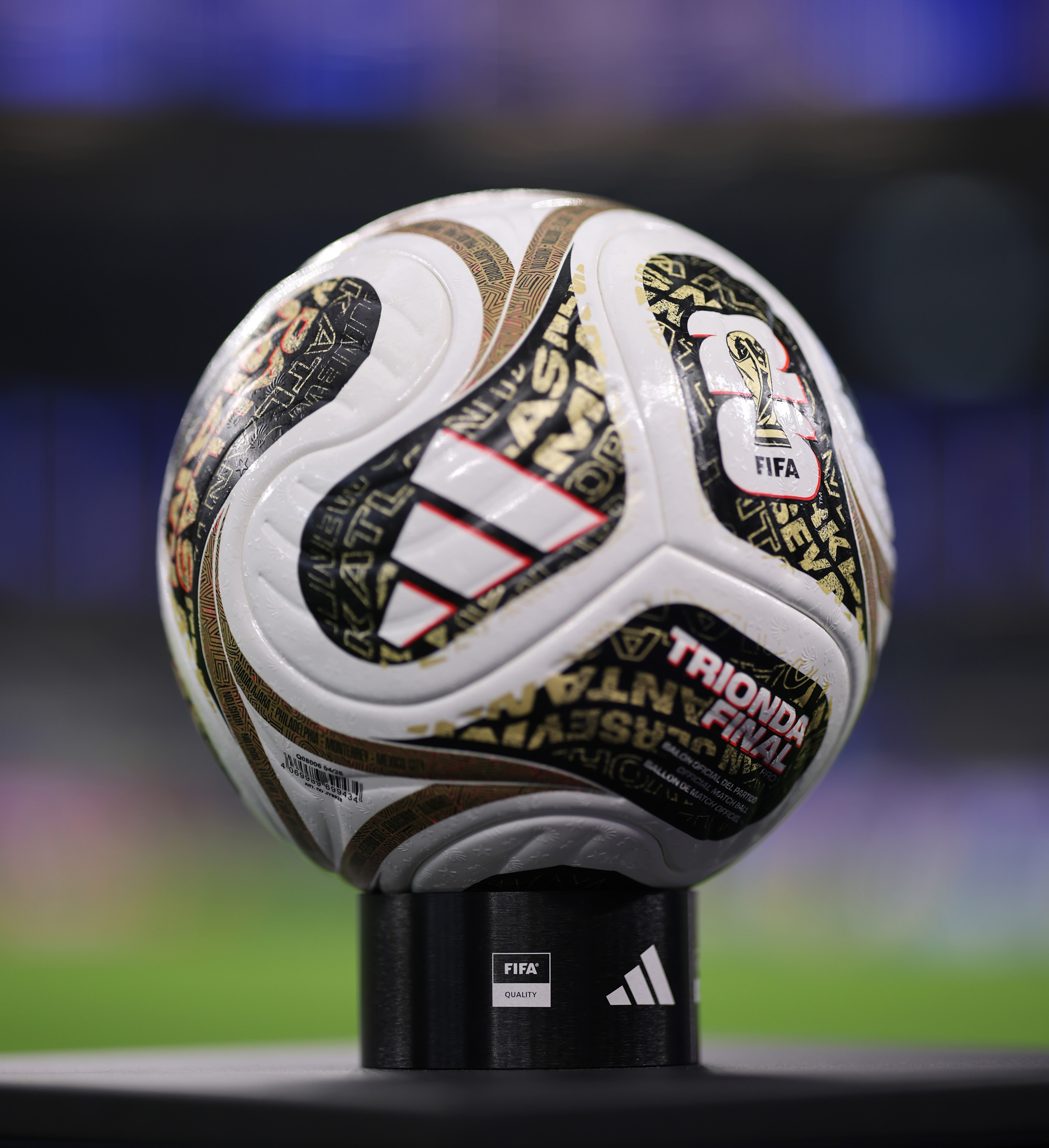 A FIFA World Cup soccer ball with the "Triunfa Final" text and Adidas logo is displayed on a stand.