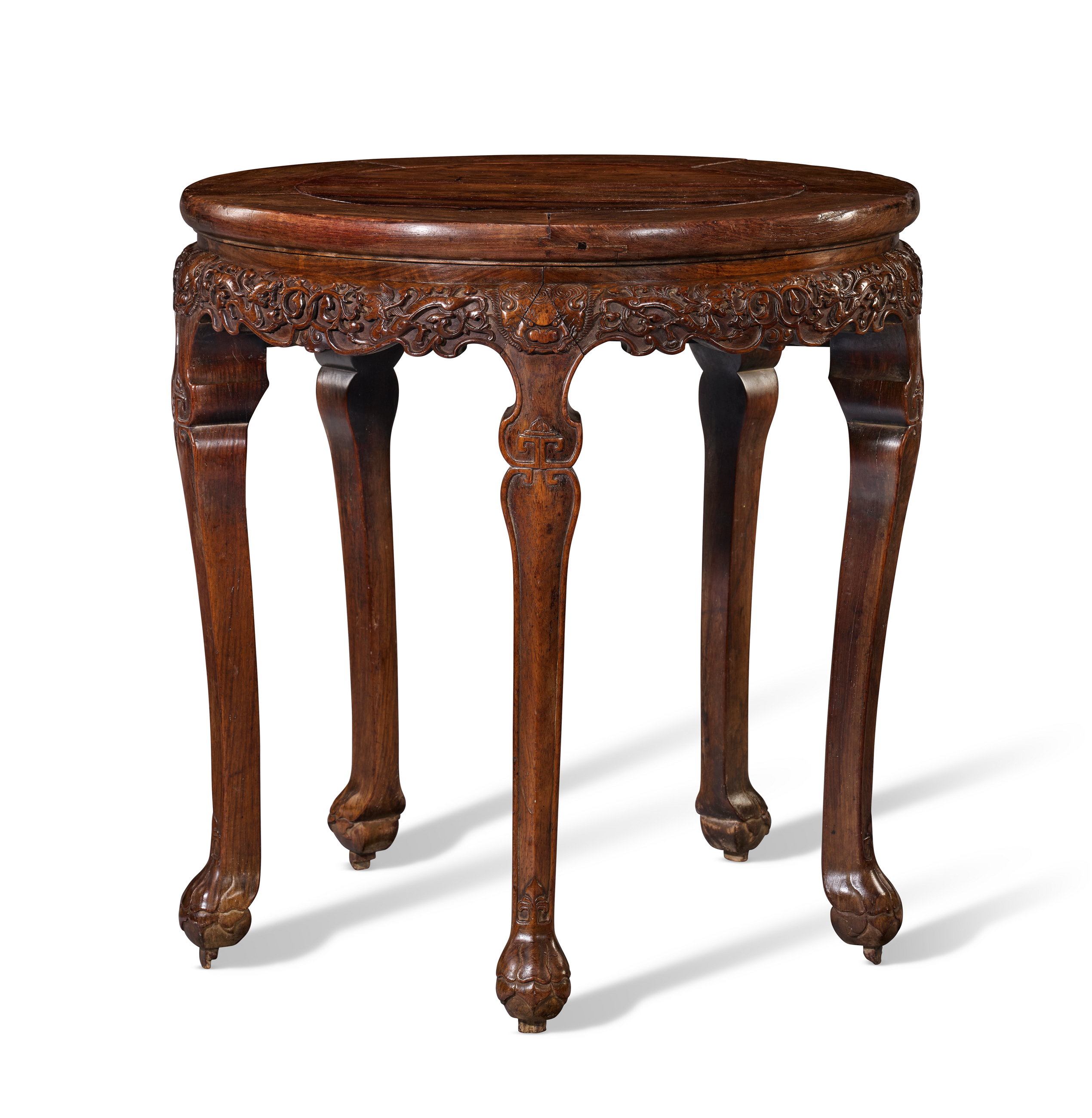 A round wooden table with carved floral designs and elegant curved legs.