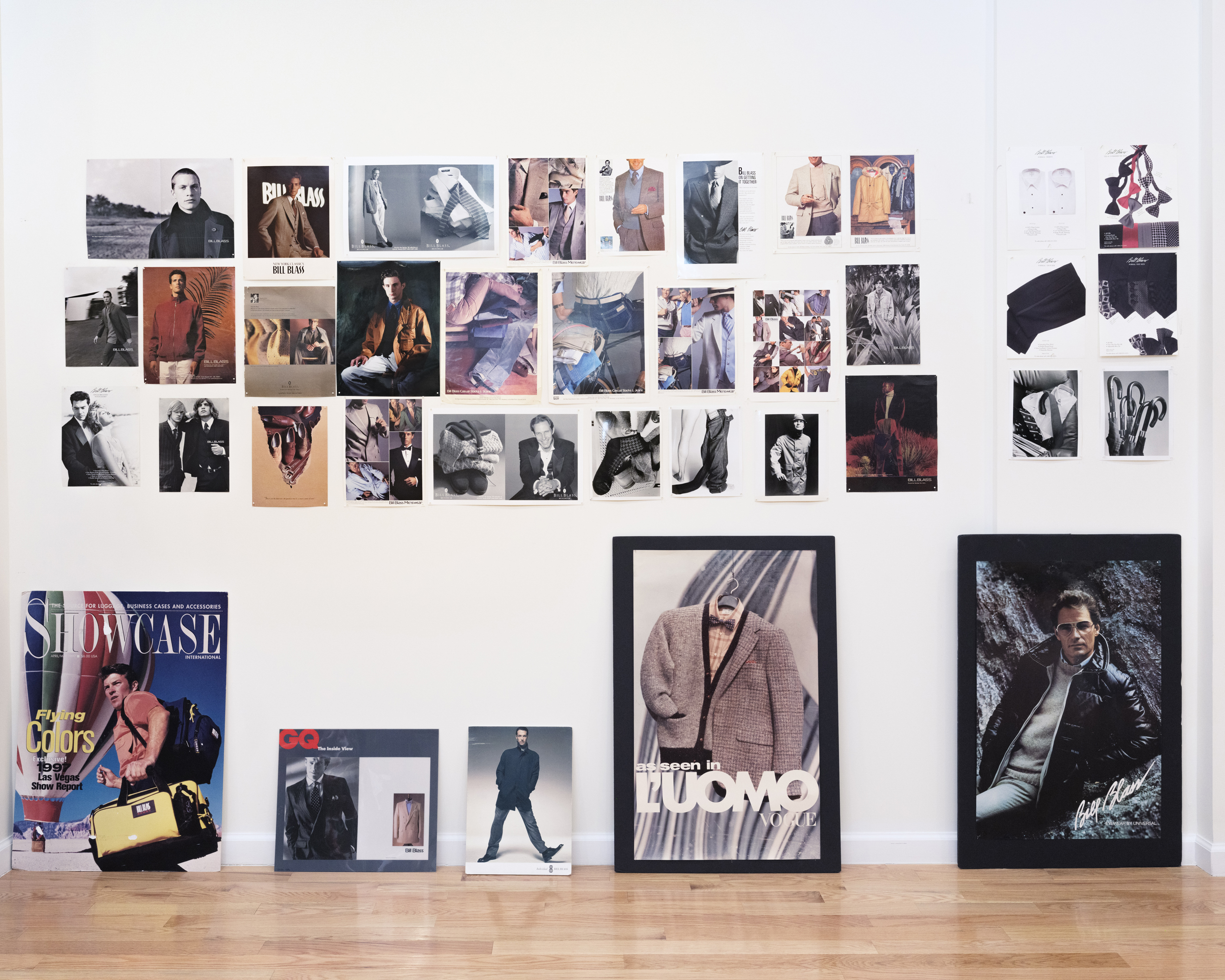 A collage of fashion magazine clippings and posters is arranged on a white wall and floor.