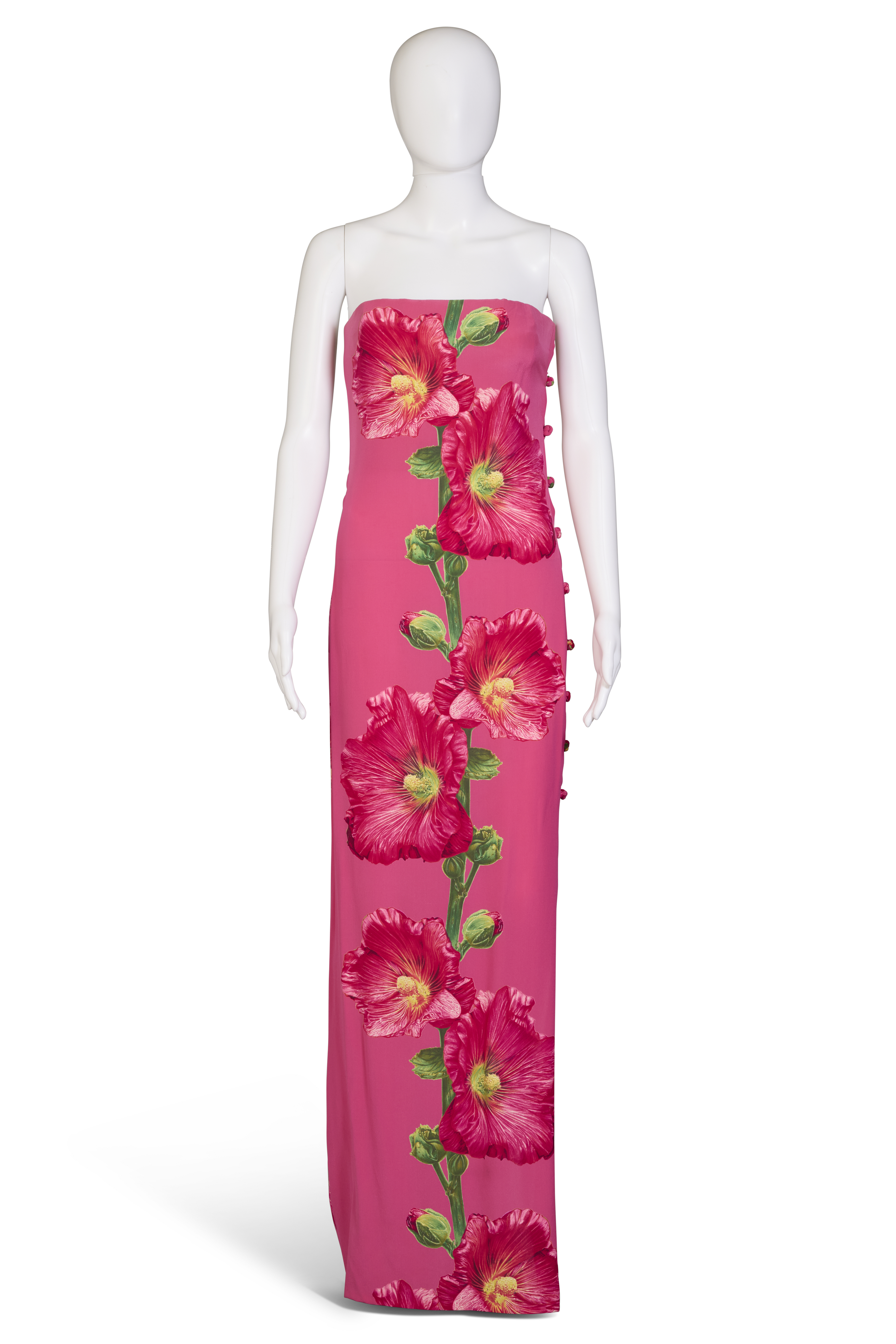 A strapless pink dress with large vertical red floral prints is displayed on a mannequin.