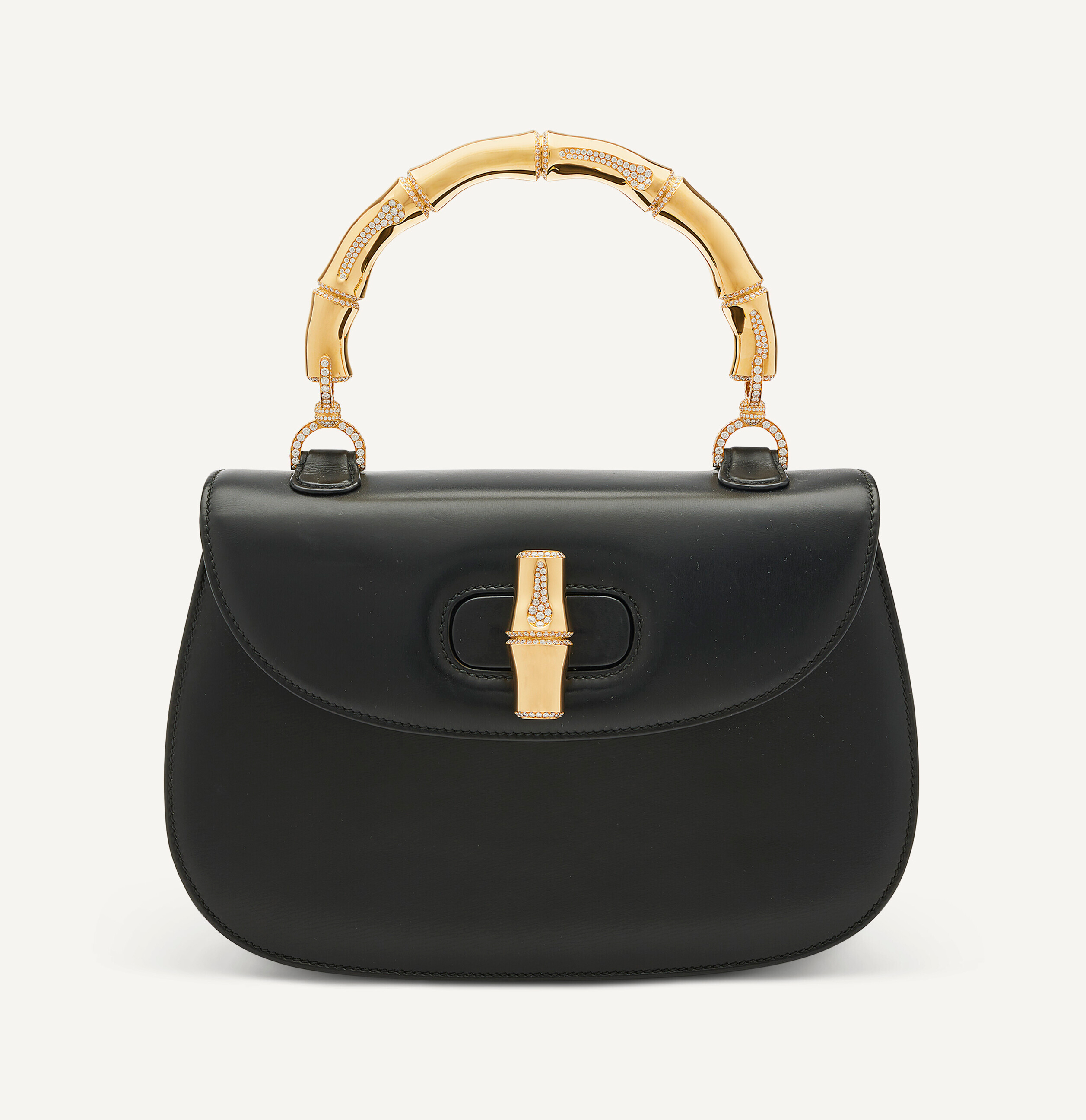 A black handbag with a gold bamboo-shaped handle and clasp, adorned with small sparkling stones.
