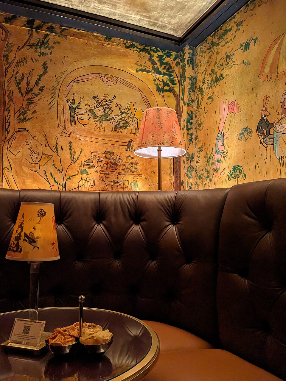 A cozy booth with whimsical wall art, warm lighting, and snacks on a round table.
