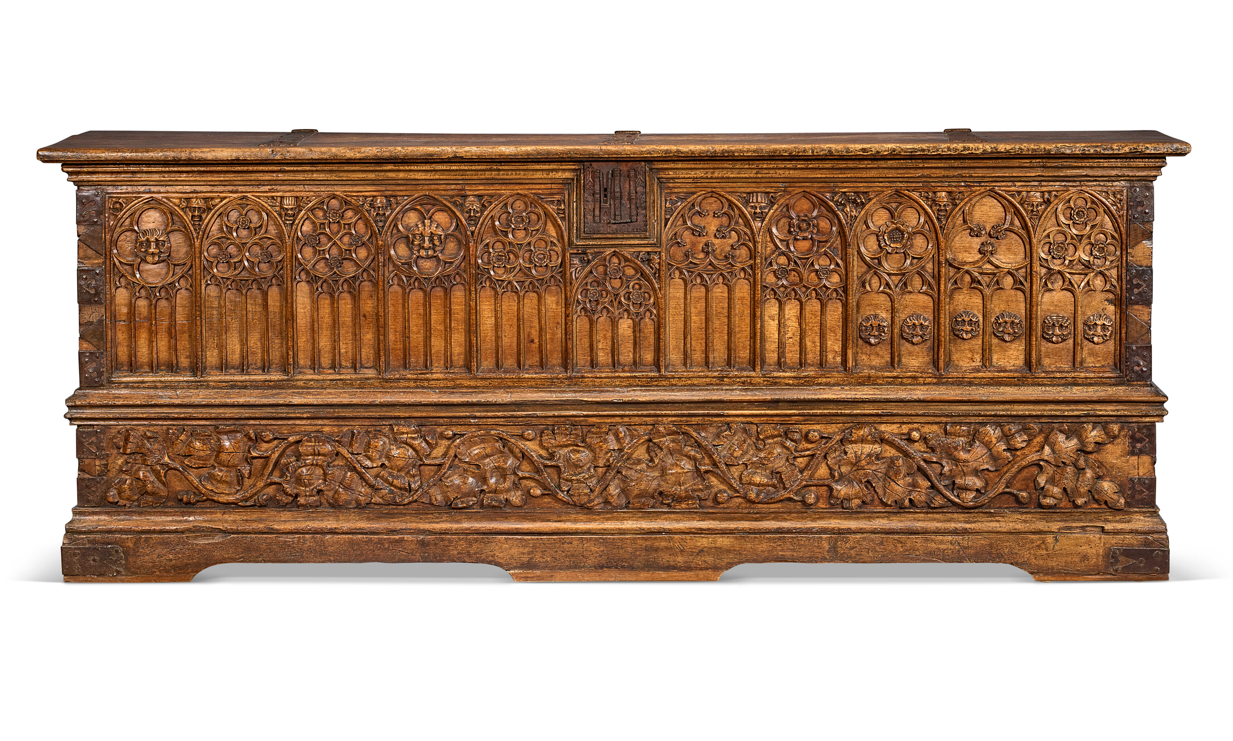 An intricately carved wooden chest features Gothic arches and floral motifs on its front panel.
