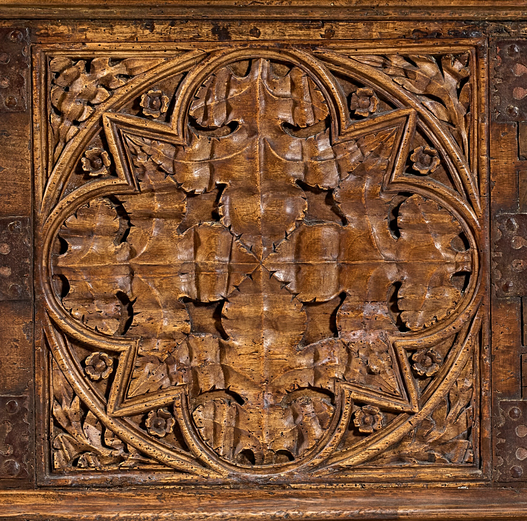 Intricately carved wooden panel with floral and geometric patterns in a square frame.