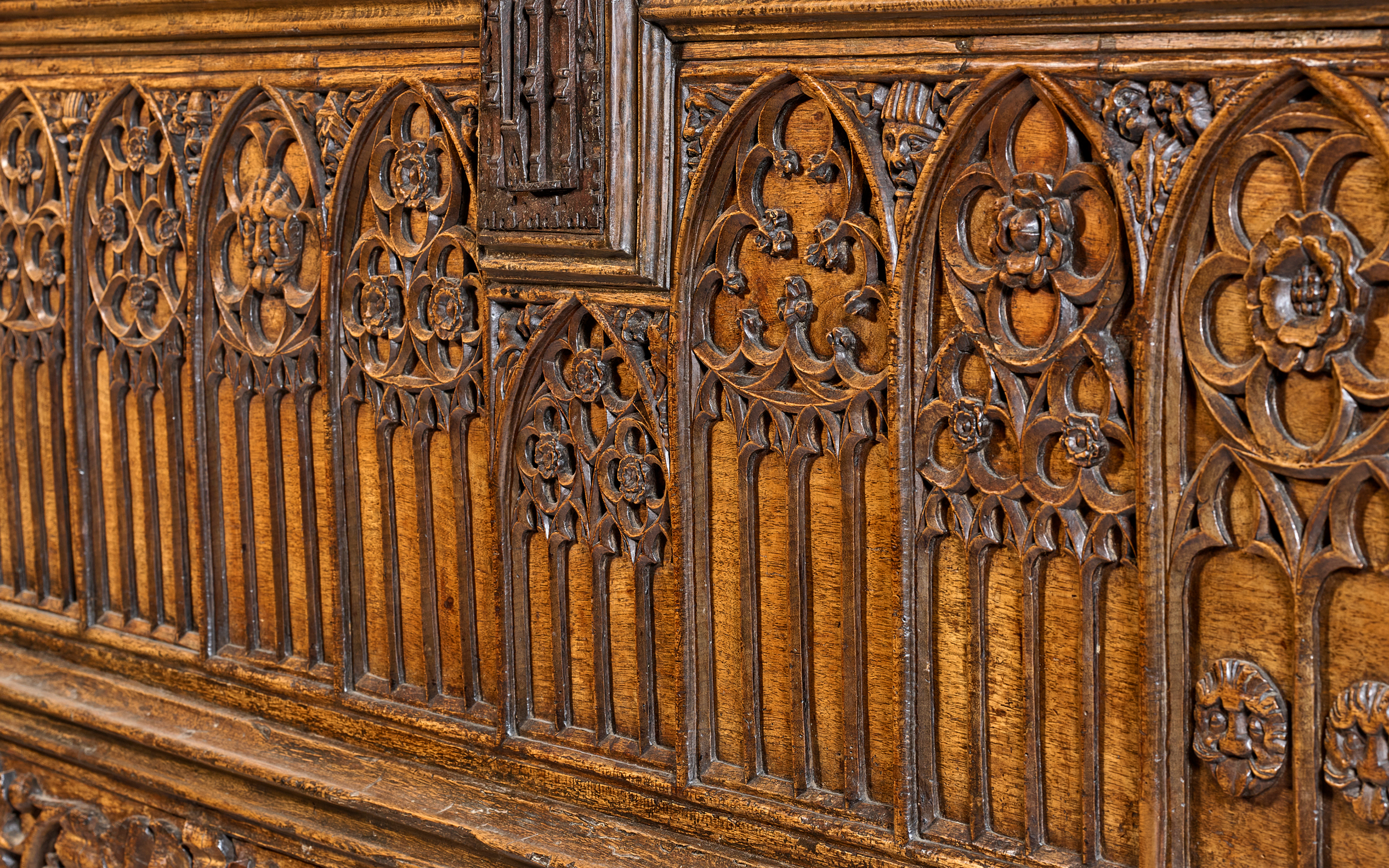 The image shows intricate Gothic-style wood carvings with floral and arched patterns.