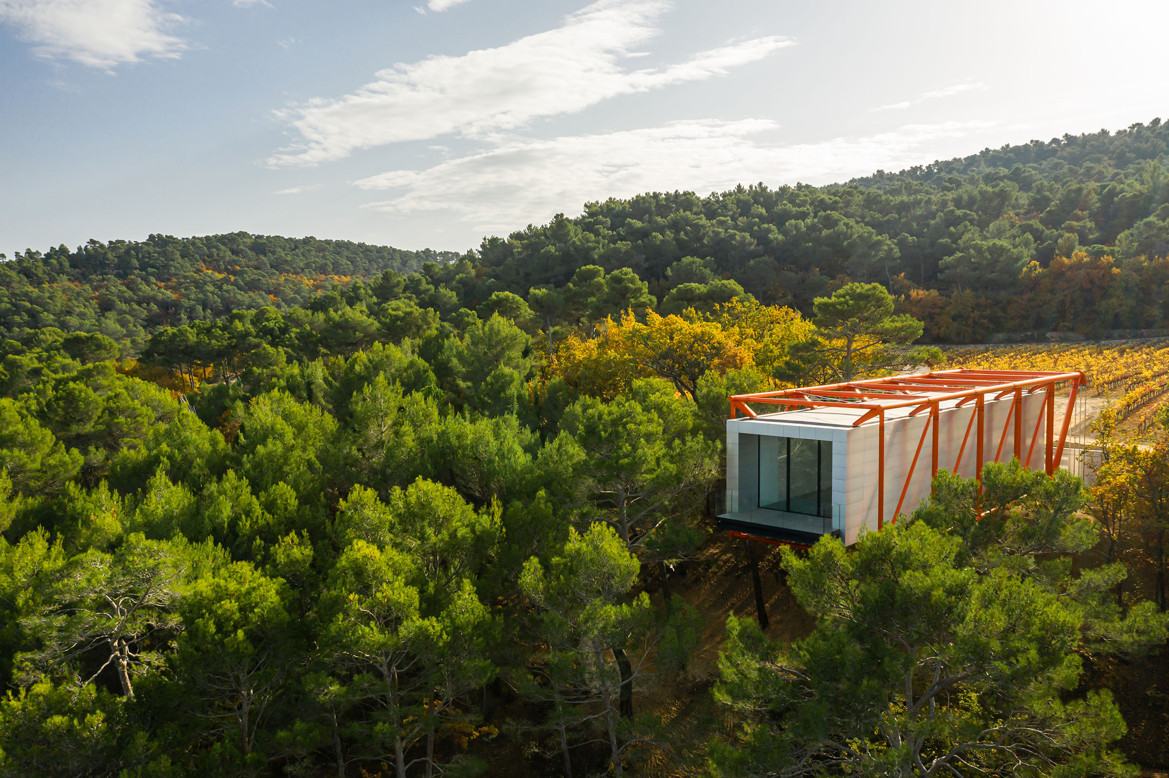 The cantilevered gallery created by Richard Rogers, with its bright-orange beams, appears to hang perilously off the top of a hill