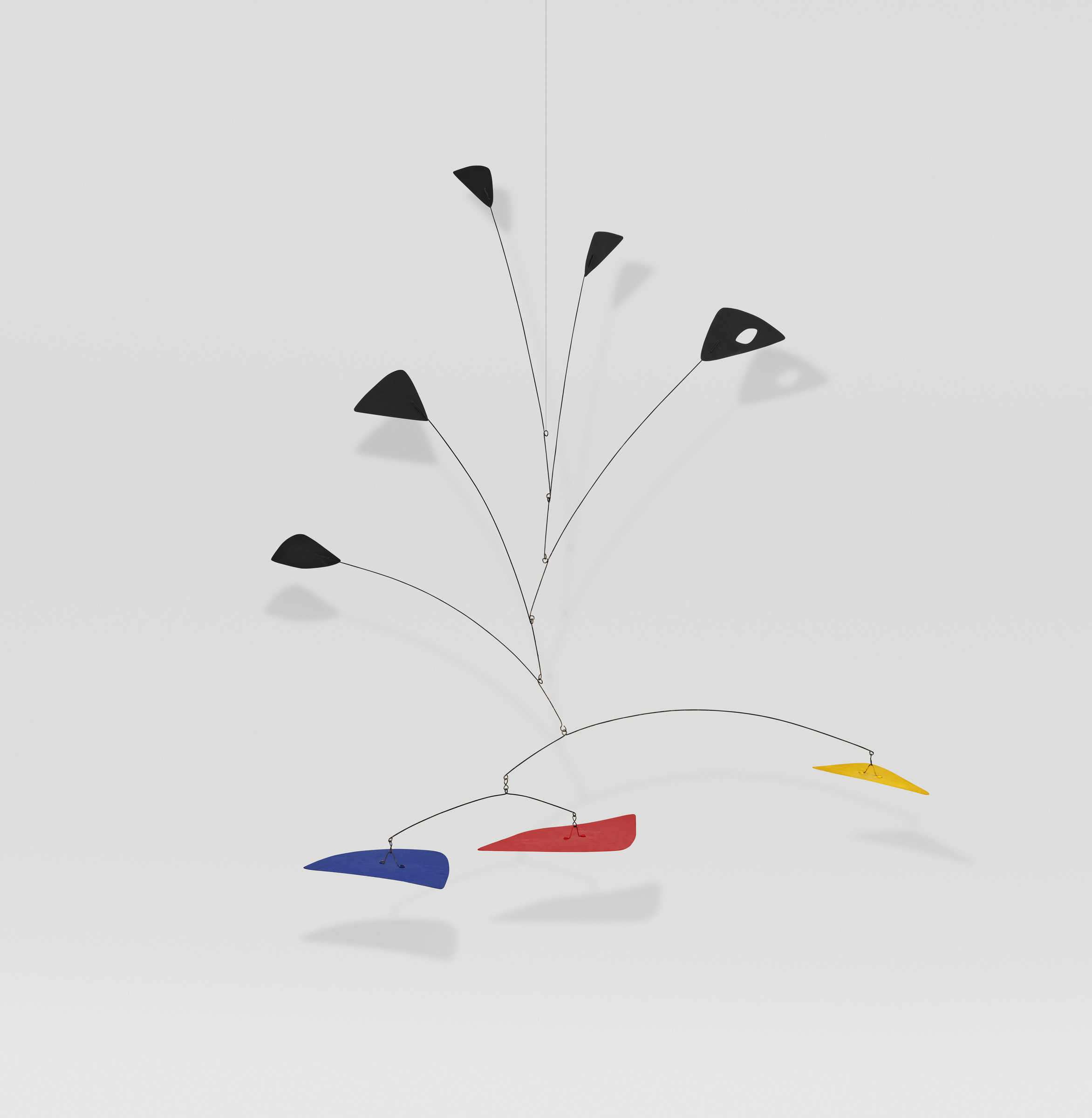 A hanging mobile with black, blue, red, and yellow abstract shapes suspended from wires.