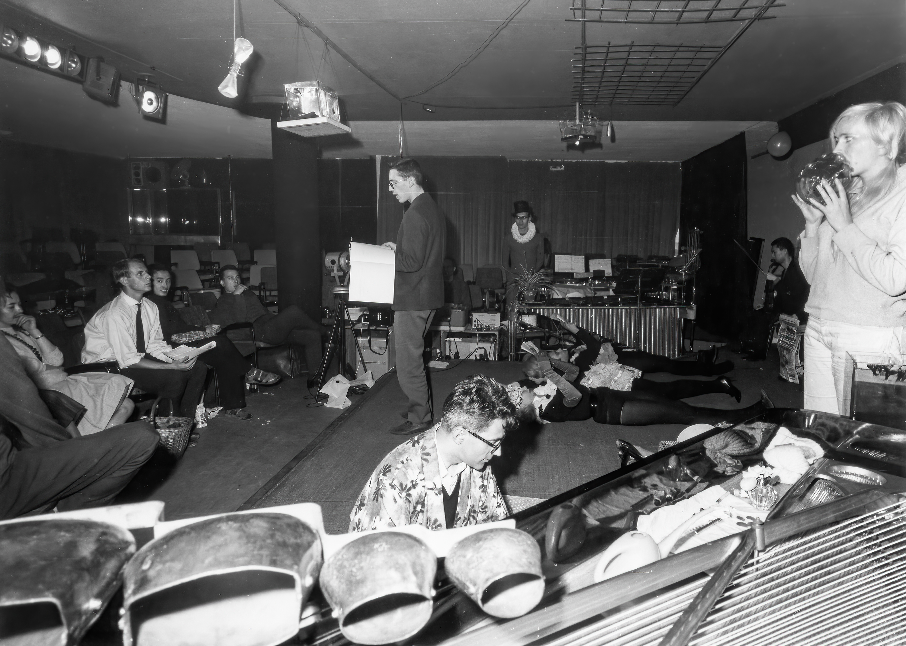A group of people engages in a creative or experimental performance in a room with various props.
