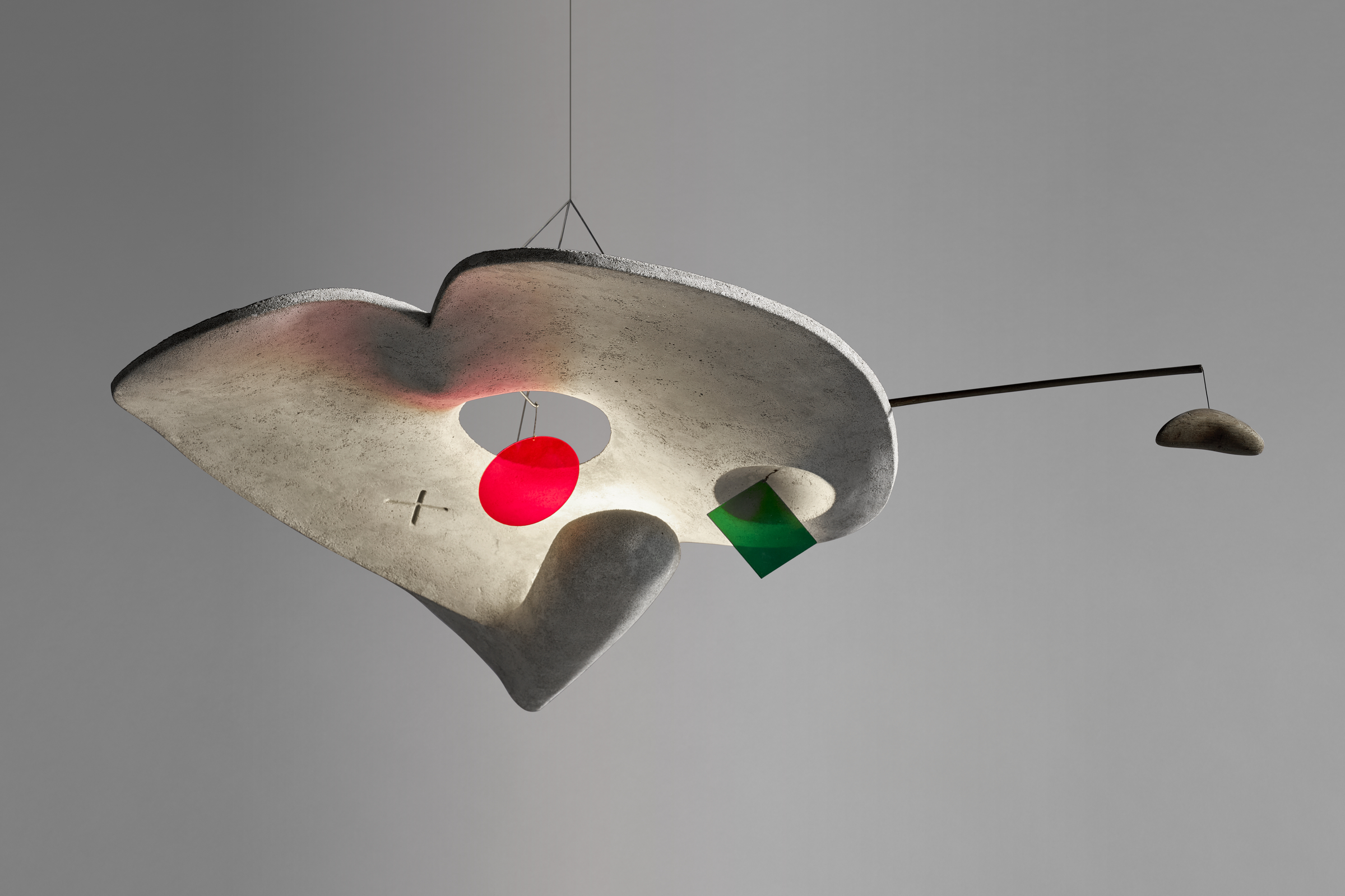 A modern hanging sculpture with abstract shapes, featuring a red sphere and a green cube.