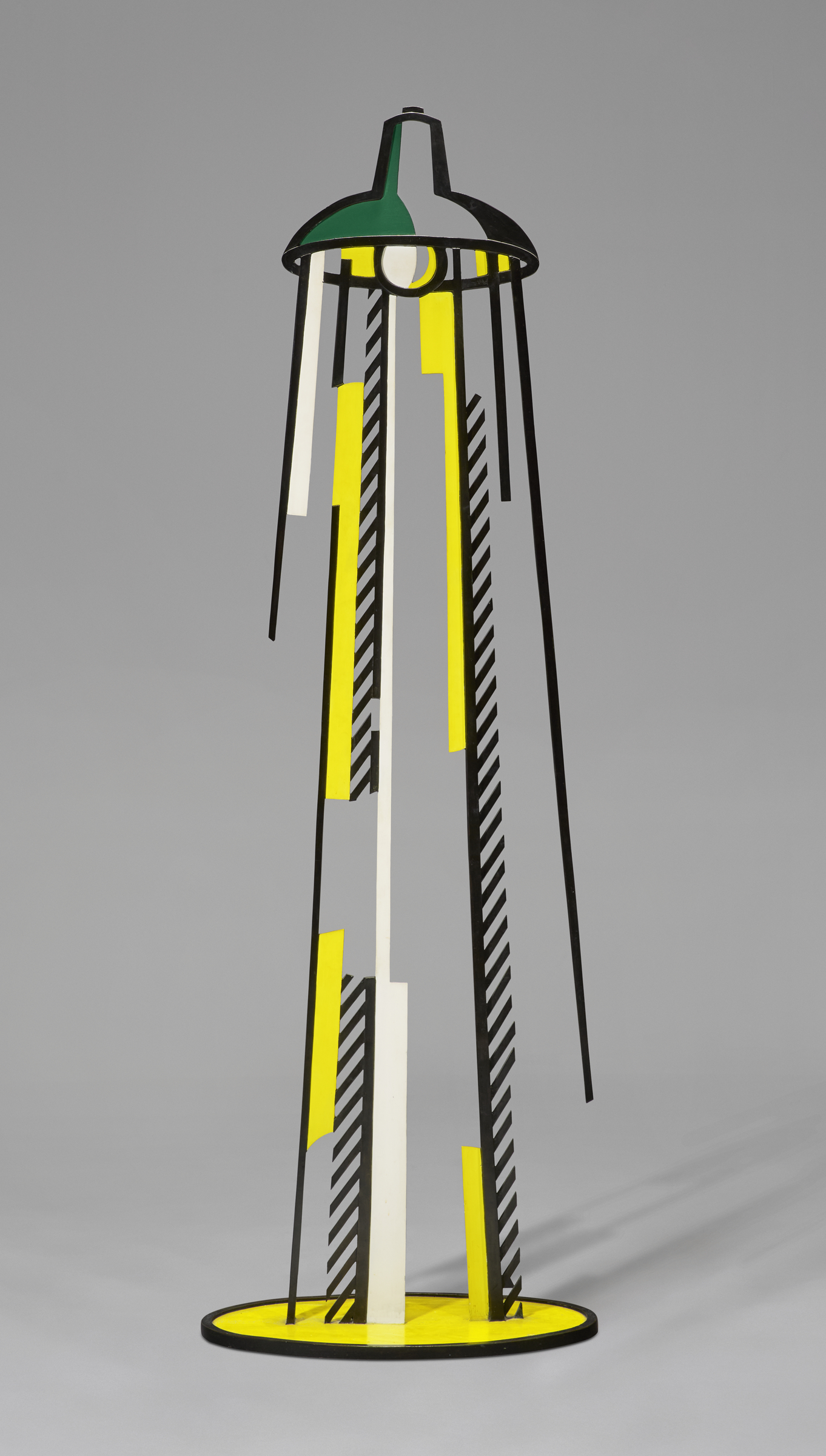 A modern sculpture of a stylized lamp with yellow, black, white, and green geometric elements.