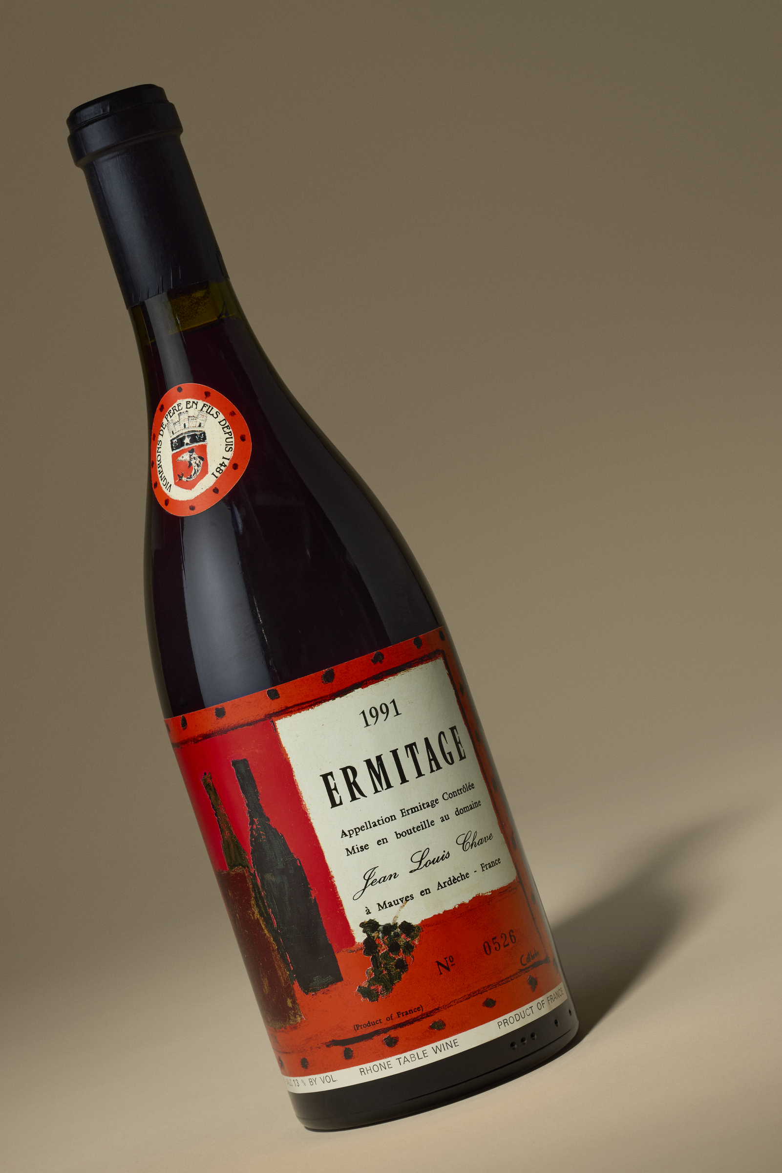 A bottle of 1991 Ermitage wine by Jean Louis Chave with a red and white label.