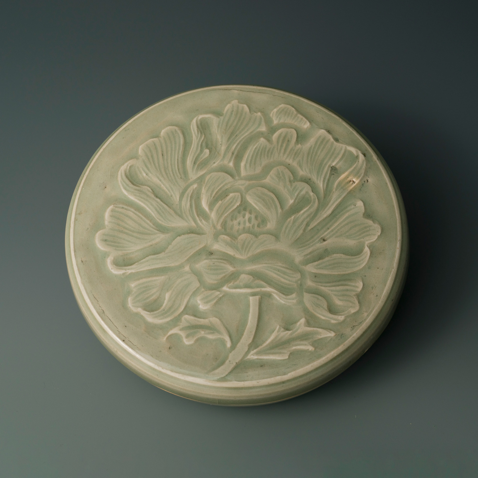 A very rare carved Longquan celadon ‘Peony’ box and cover, Song-Yuan Dynasty (960-1368). 17 cm (6¾ in) diam. Estimate: HK$400,000-600,000. Offered in The Songde Tang Collection - Song Dynasty Ceramics on 3 December at Christie’s in Hong Kong
