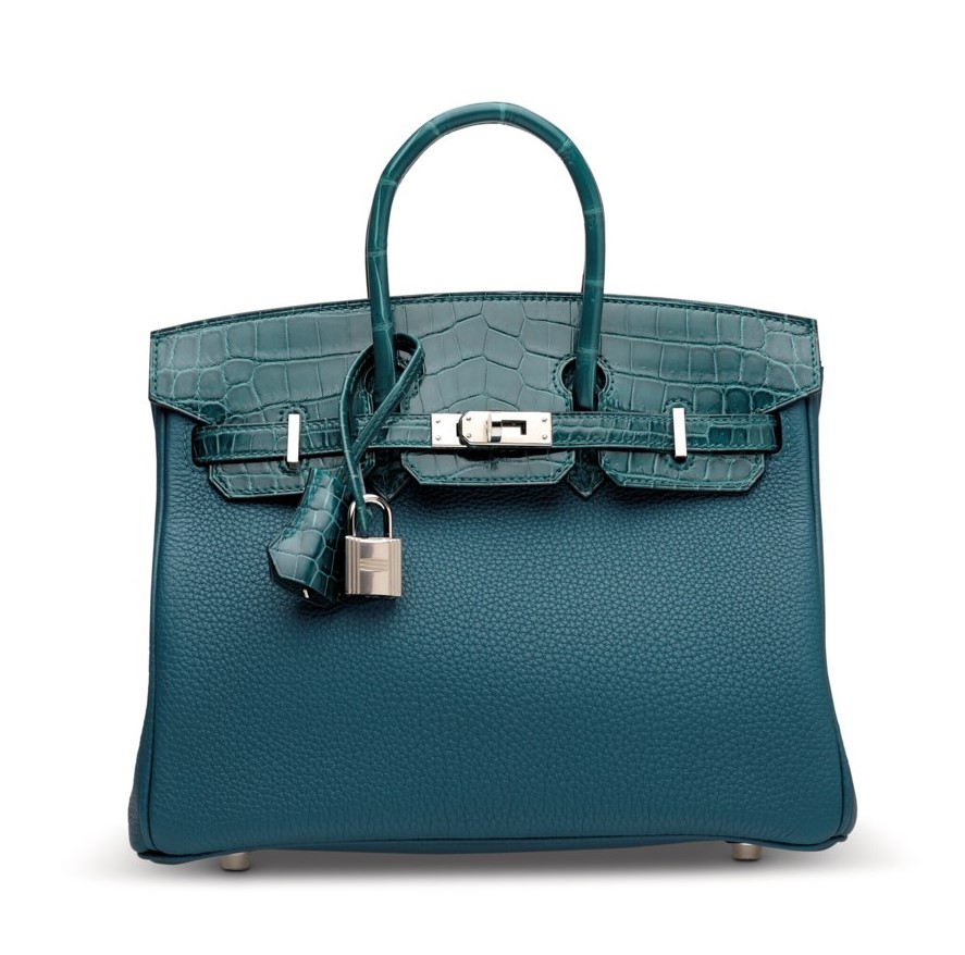 A teal luxury handbag with a textured body, crocodile-patterned flap, and silver hardware.