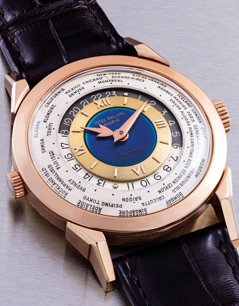 A luxurious Patek Philippe wristwatch with a world time dial and a blue and gold color scheme, paired with a brown leather strap.