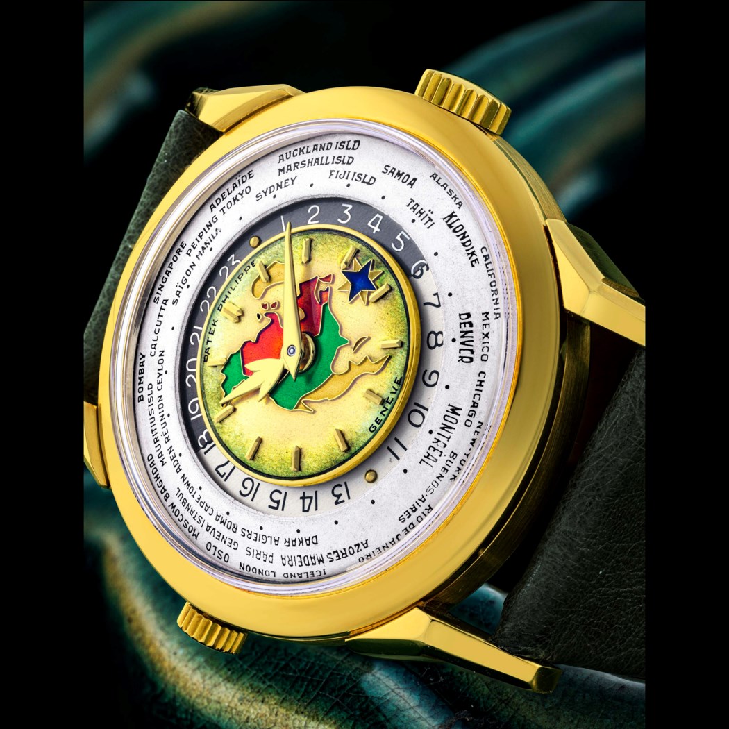 A detailed world time watch with a colorful map and city names on a rotating outer ring, set in a gold casing.