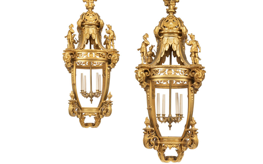 Two ornate golden lanterns with intricate designs and figures, displayed against a white background.