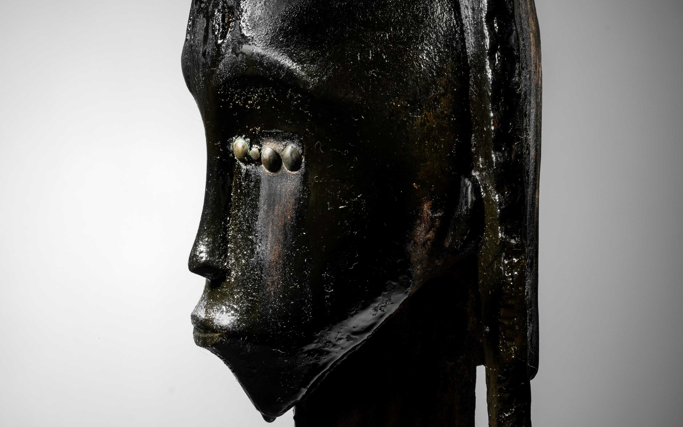 The image shows a statue with a textured and glossy surface placed against a light gray background.