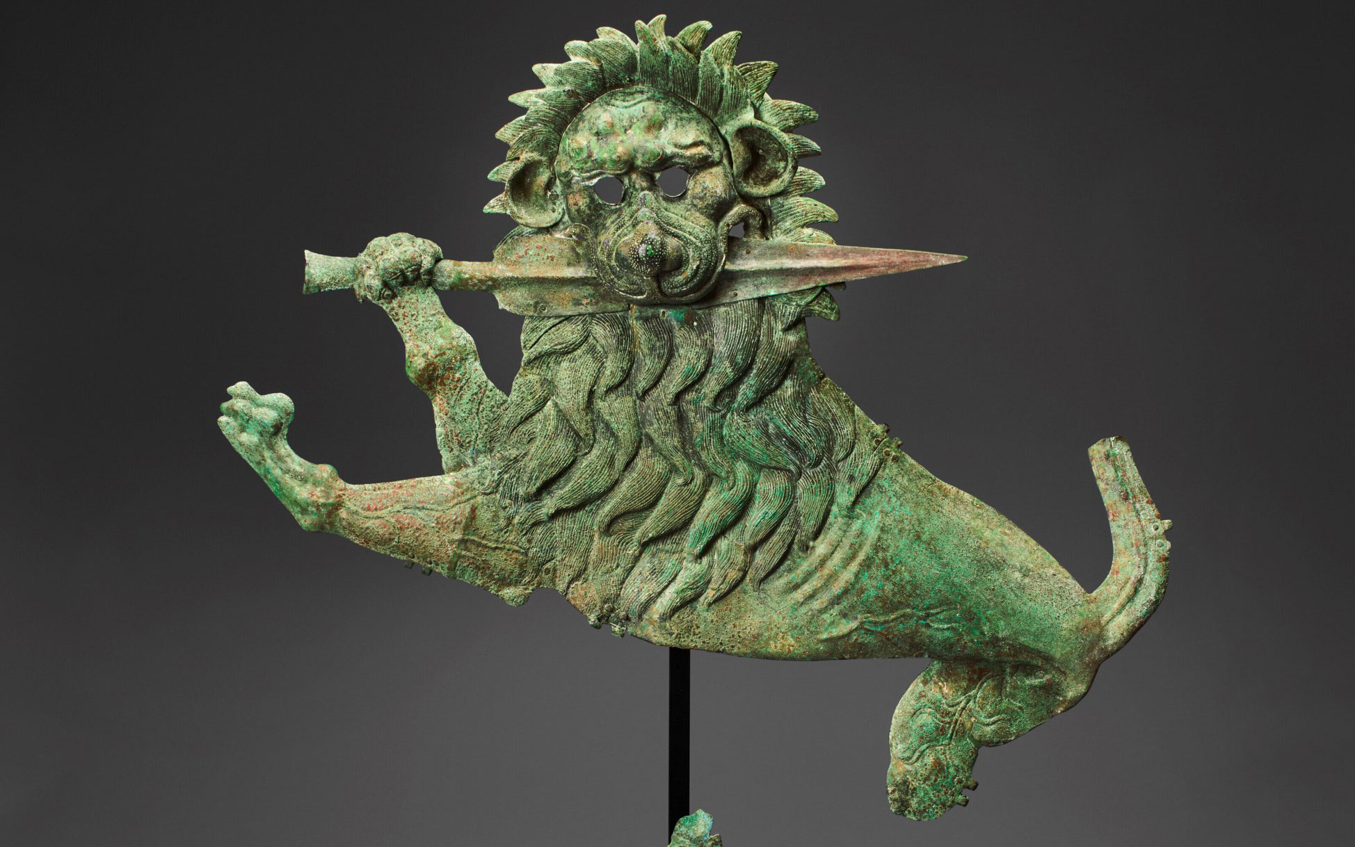 A bronze sculpture depicting a lion with a mane and tail, holding a sword, shown in a dynamic pose.
