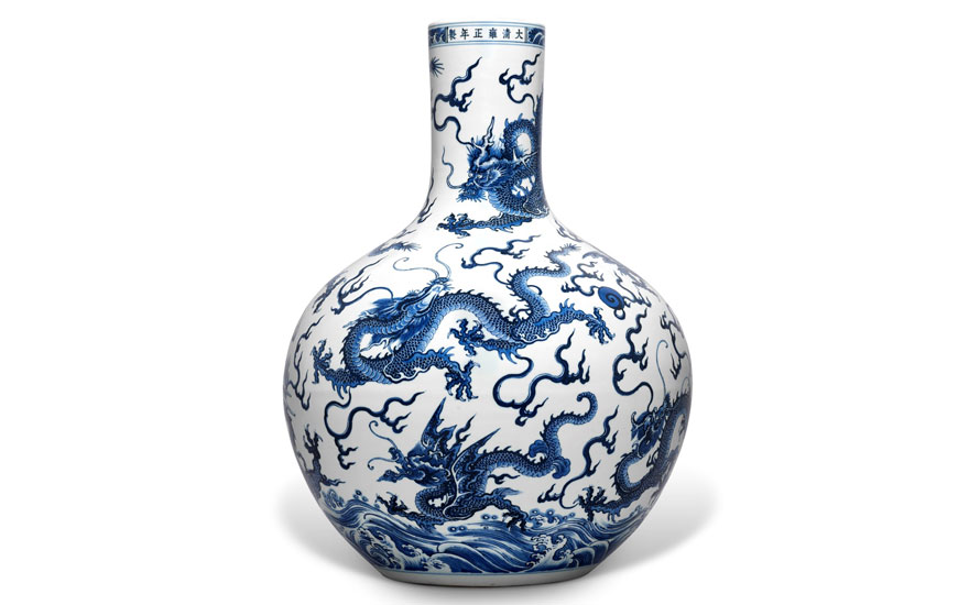 White and blue porcelain vase with intricate dragon designs and wave patterns.