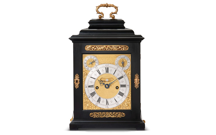 An ornate black and gold antique bracket clock with Roman numerals and decorative elements.