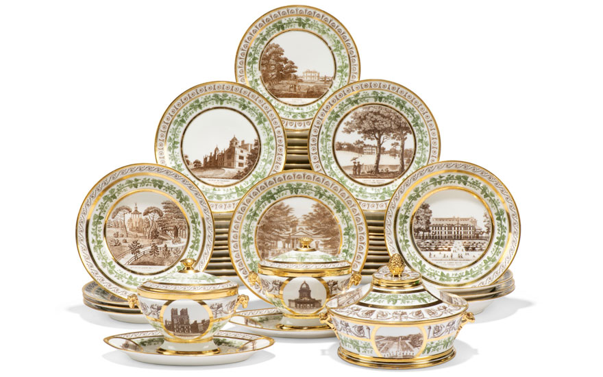 An elegant set of china with green and gold trim, featuring detailed scenes of various landscapes on each piece.