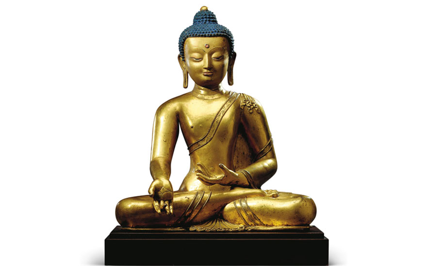 A golden statue of a seated figure, dressed in ornate robes, posed in a meditative position.