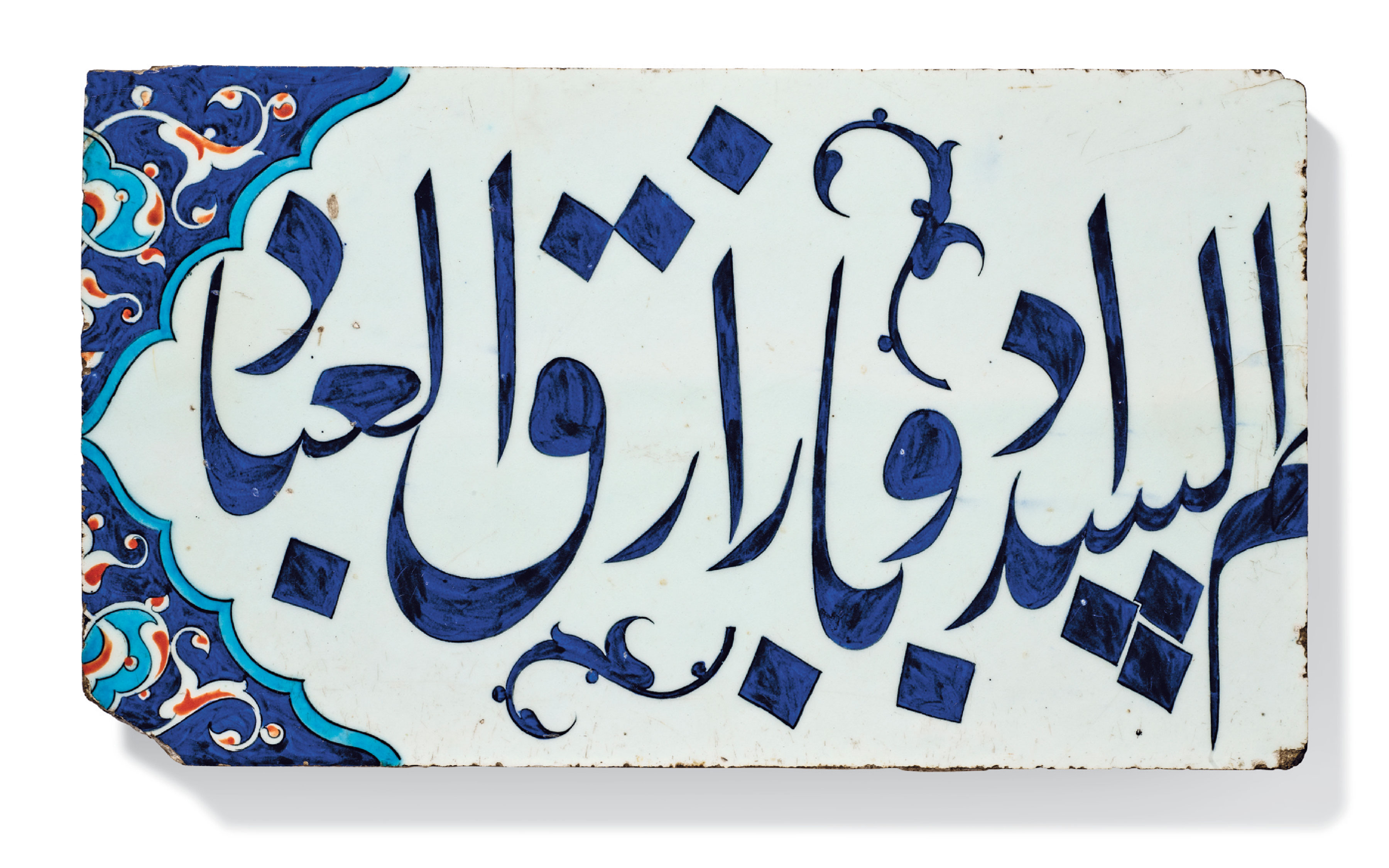 An antique ceramic tile featuring intricate blue Arabic calligraphy with ornamental designs in blue and orange.