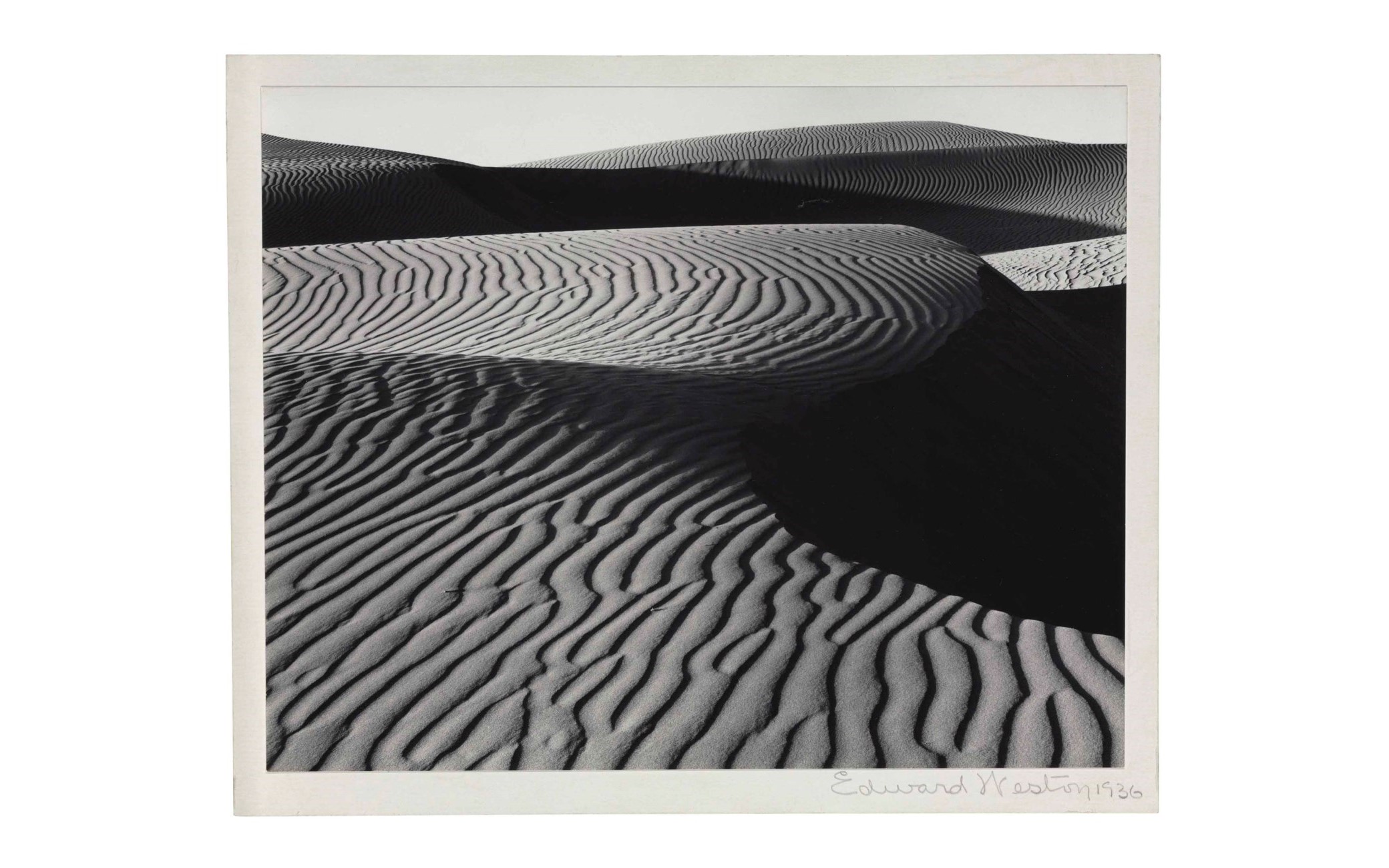 一張帶有漣漪圖案的紋理沙丘的黑白照片，由Edward Weston於1936年簽名。