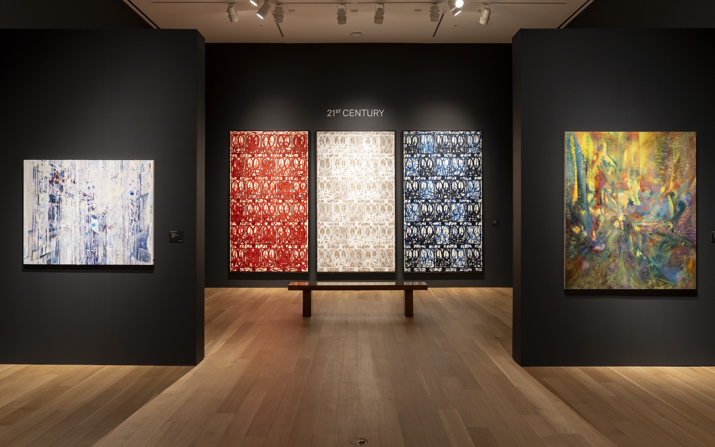 A modern art gallery room displaying various colorful and abstract paintings on well-lit walls.