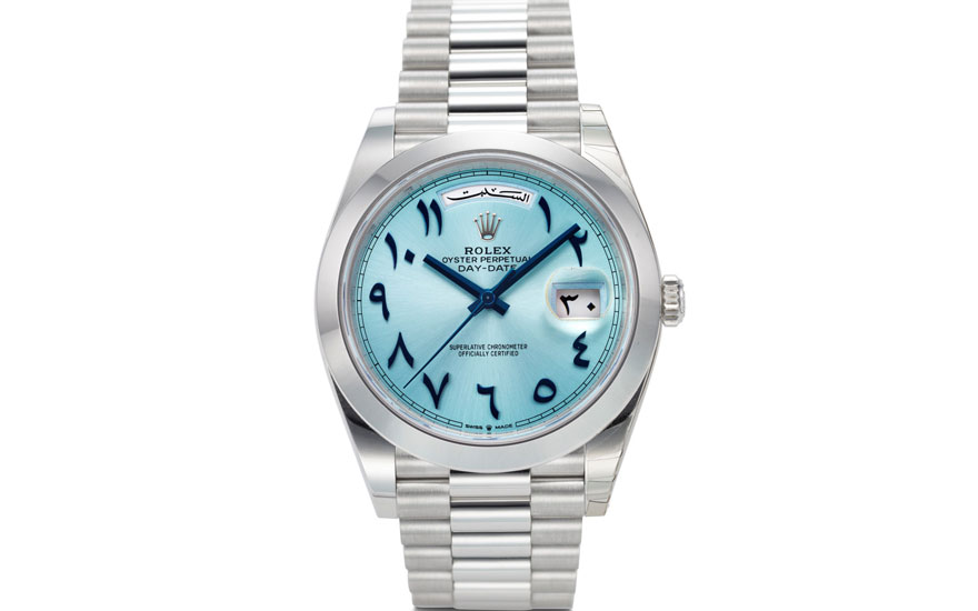 A Rolex Oyster Perpetual Day-Date watch with a light blue dial and Arabic numerals, featuring day and date display.
