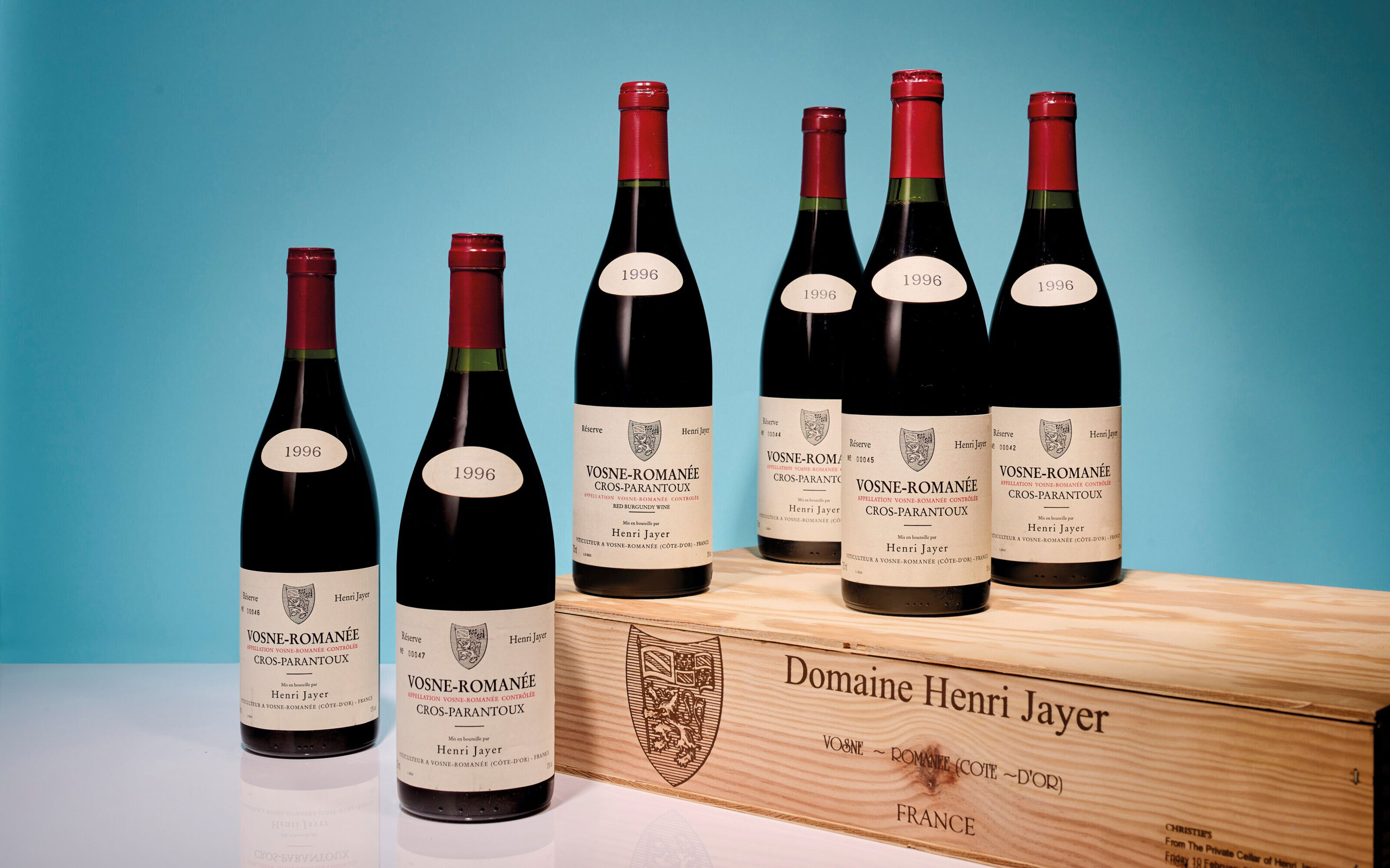 五瓶 Vosne-Romanée Cros Parantoux 1996 葡萄酒陳列在一個標有“Domaine Henri Jayer”的木箱前。