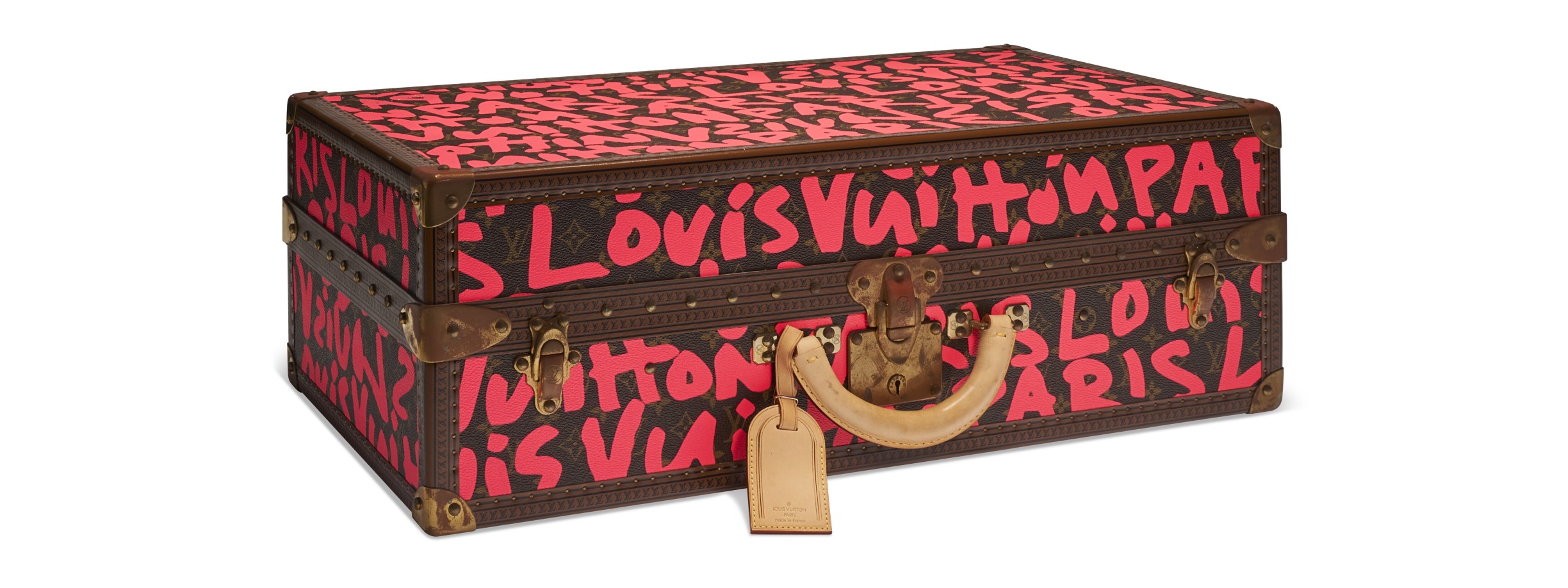 A vintage Louis Vuitton trunk with bold red graffiti-style lettering on a dark background.