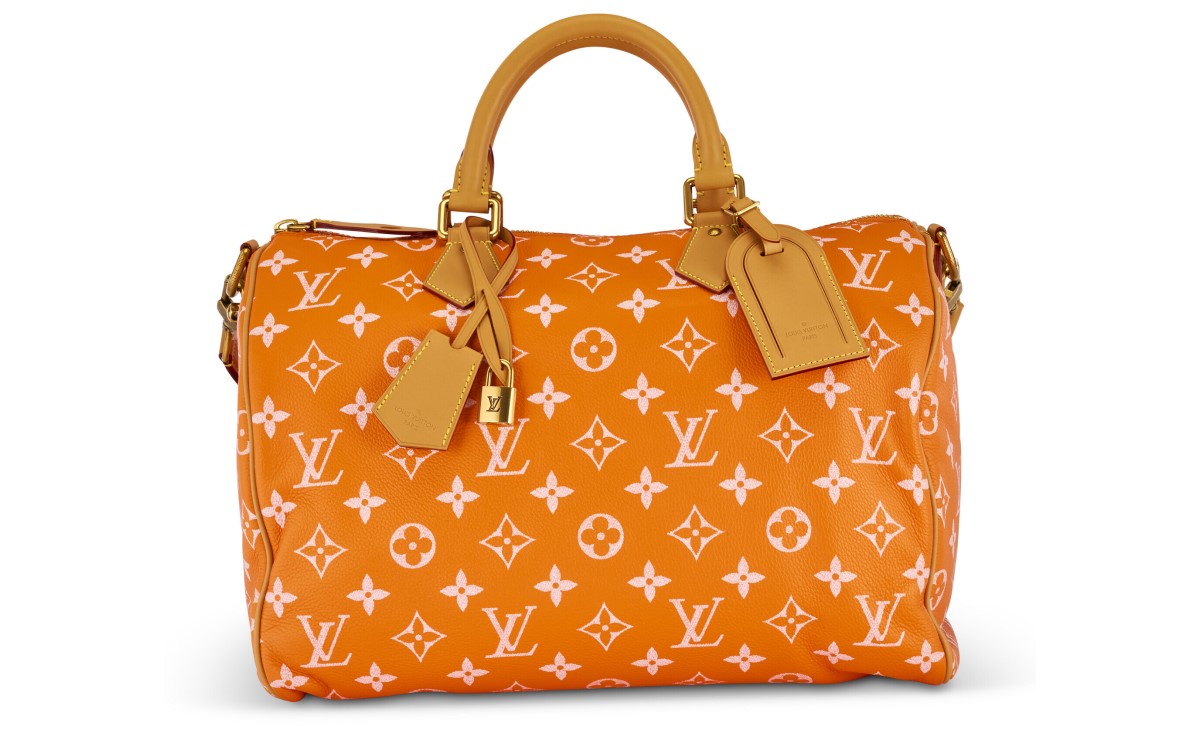An orange Louis Vuitton handbag with white monogram pattern and tan leather handles.
