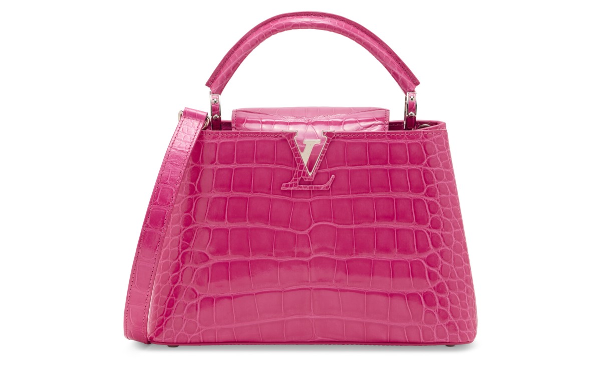A pink crocodile-embossed handbag with a top handle and a silver "V" accent on the front.