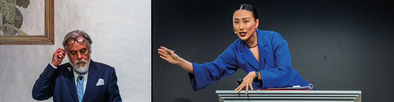 The image shows two people in an auction room: a man in a suit by a painting and the auctioneer, a woman in a blue blazer gesturing at the podium.