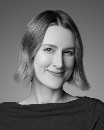 A woman with short, straight hair smiles in a black and white portrait photo.