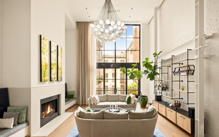 A modern living room with large windows, elegant furniture, and a stylish chandelier.