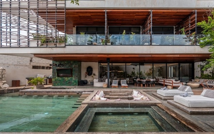 A modern house features an outdoor pool, sunken seating area, and spacious balcony.
